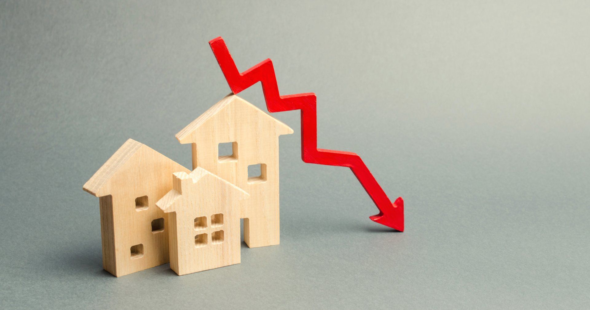 3 houten huizen met een rode hypotheekverlaging pijl