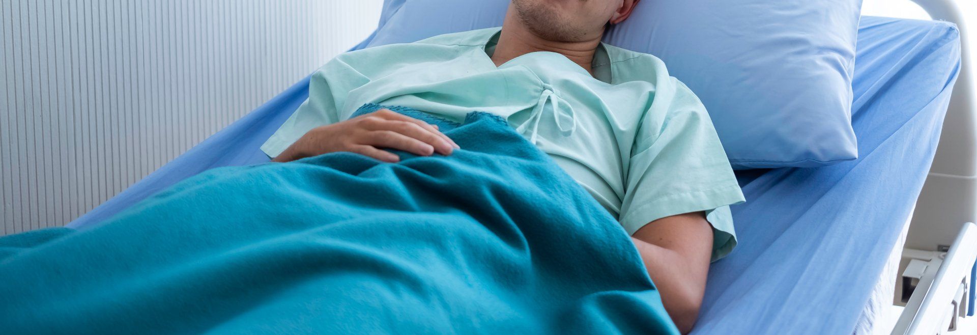 Het Mediators Collectief is op de hoogte van alle ins en outs van de Wet Verbetering Poortwachter patiënt ligt op een bed met blauw beddengoed in het ziekenhuis
