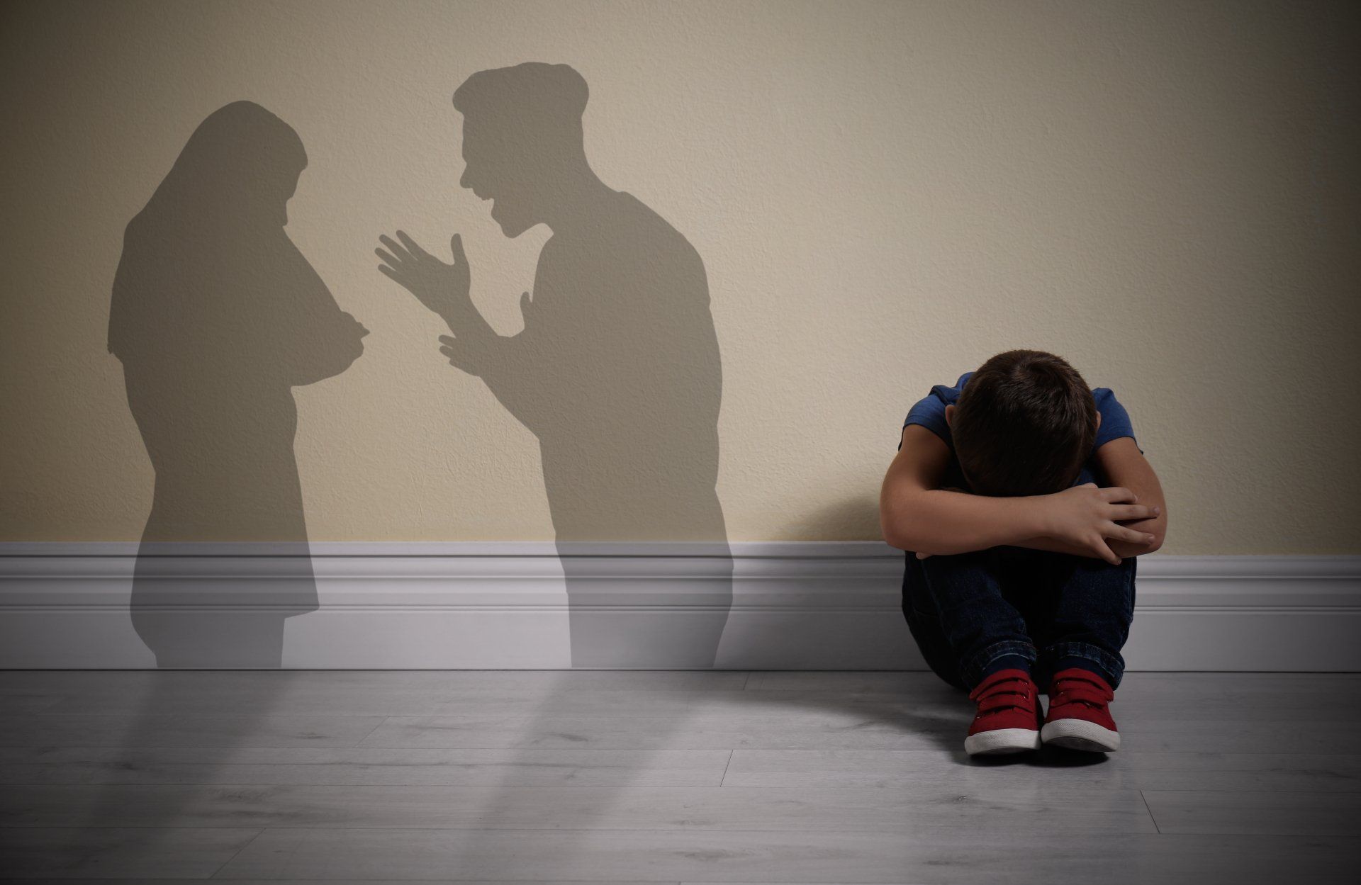 Voorkom een vechtscheiding en getraumatiseerde kinderen. Neem contact op met Het Mediators Collectief. ineengekrompen kin met vechtende ouders op de achtergrond