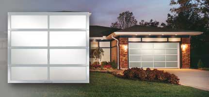 A modern home with a glass garage door; dusk setting.