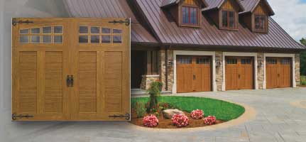 Garage doors on a house with a brown metal roof and a circular flower bed.