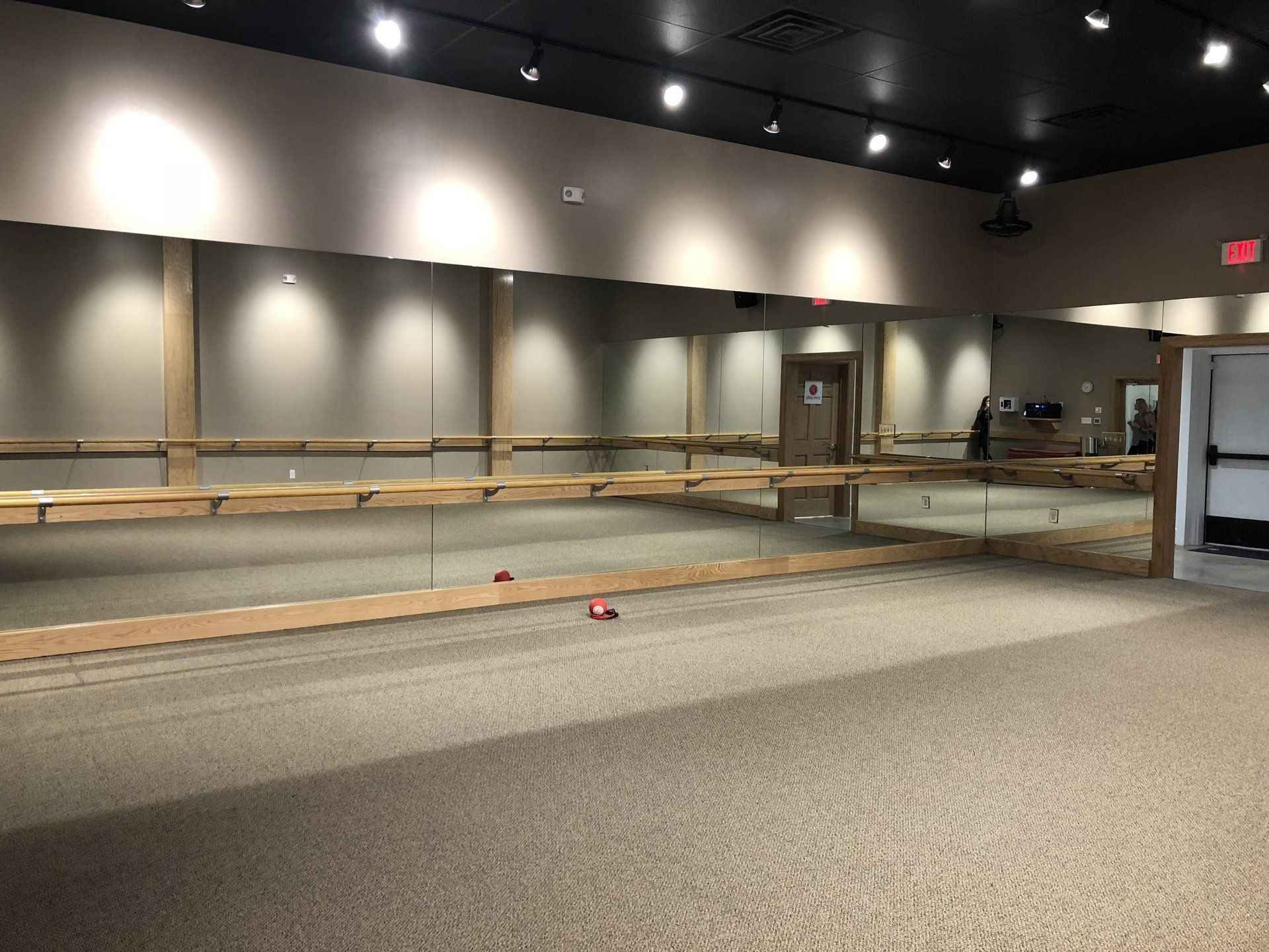 An empty dance studio with a large mirror and a wooden bar