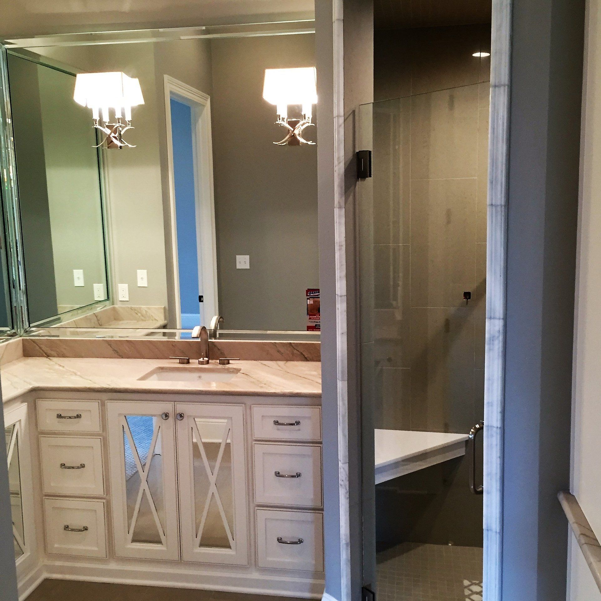 A bathroom with white cabinets and a large mirror