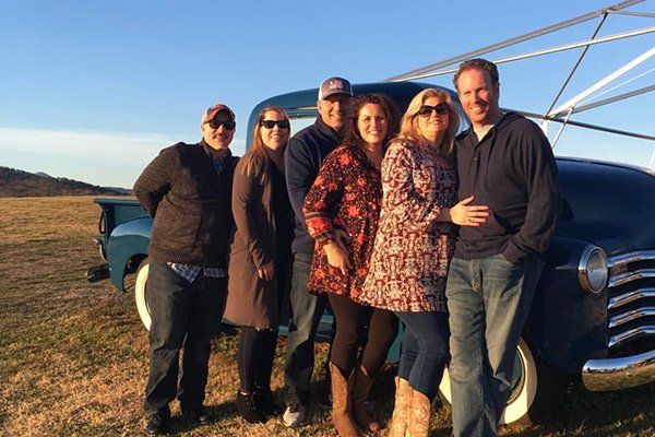 group of people posing in front of truck in field