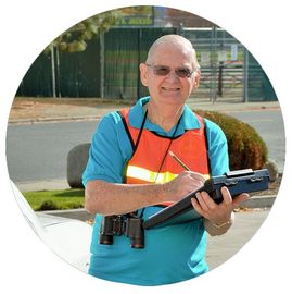 Man wearing a turquoise shirt and reflective best writing on a clipboard