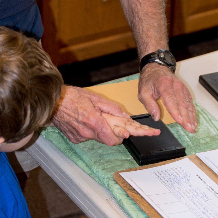 Adult fingerprinting a young child. 