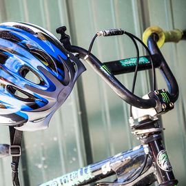 Black Bike with a Blue Helmet hanging off of the handlebars