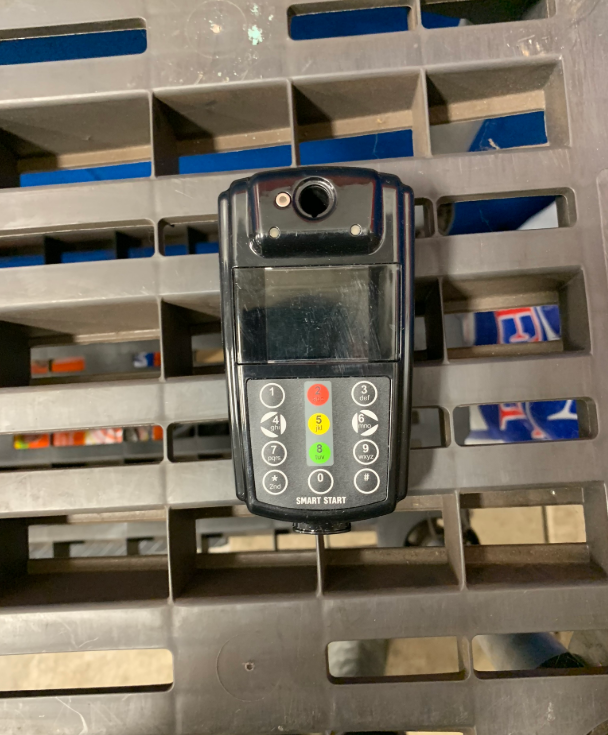 Black handheld device with buttons, camera lens, and screen on a gray pallet.