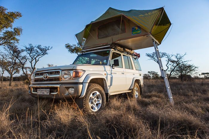 Toyota safari 4x4 vehicle in the african bush with a tent installed on it's roof