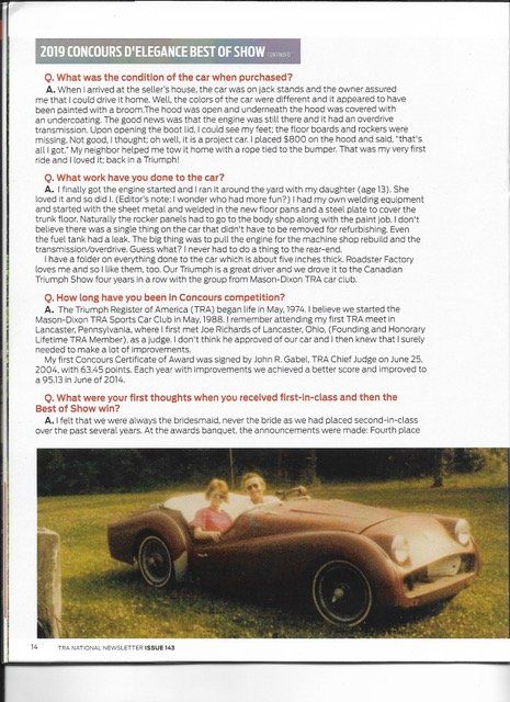 Two people in a classic red car, smiling, in a grassy field.