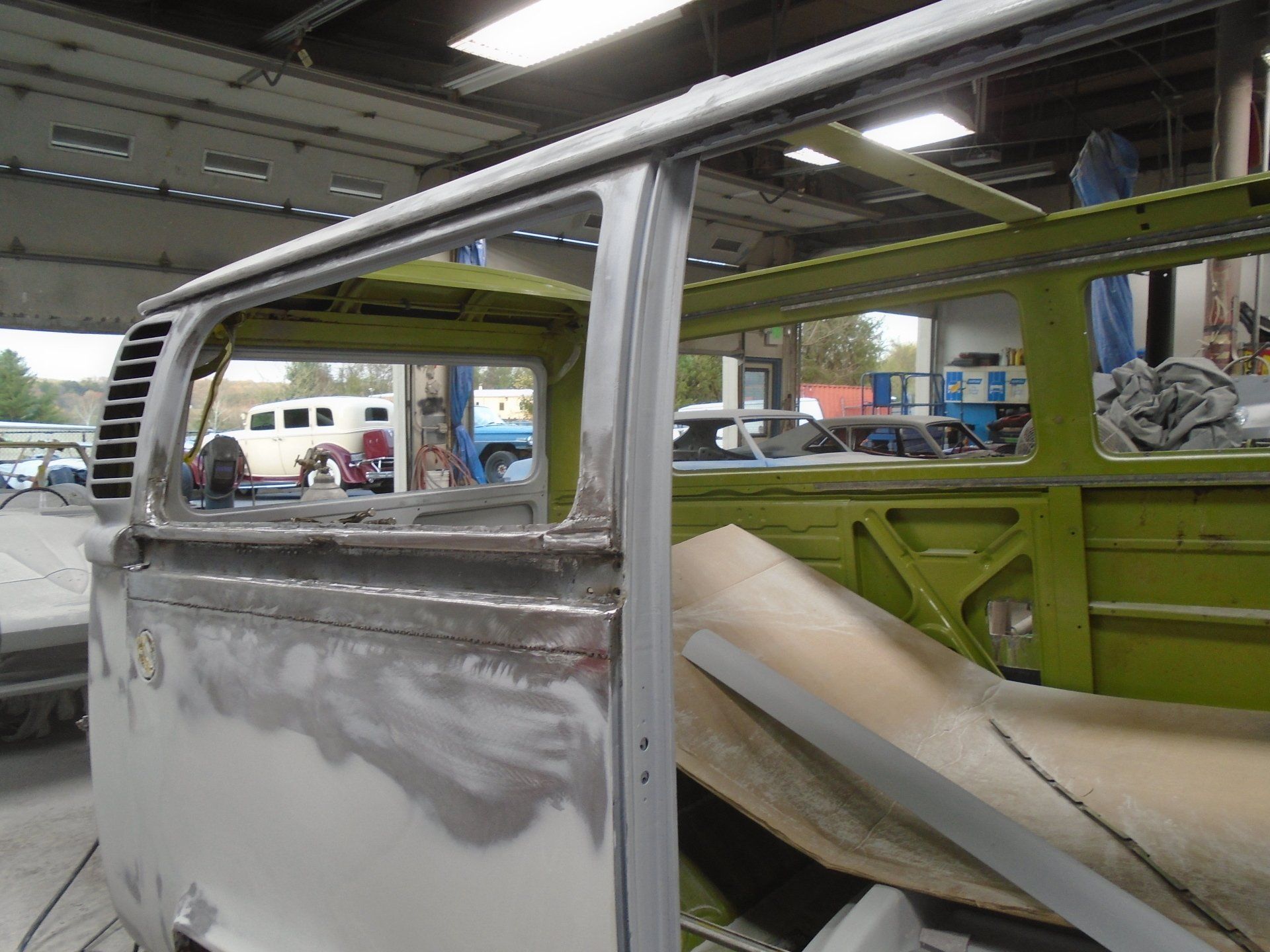 Volkswagen bus undergoing restoration inside a garage; partially disassembled with exposed frame.