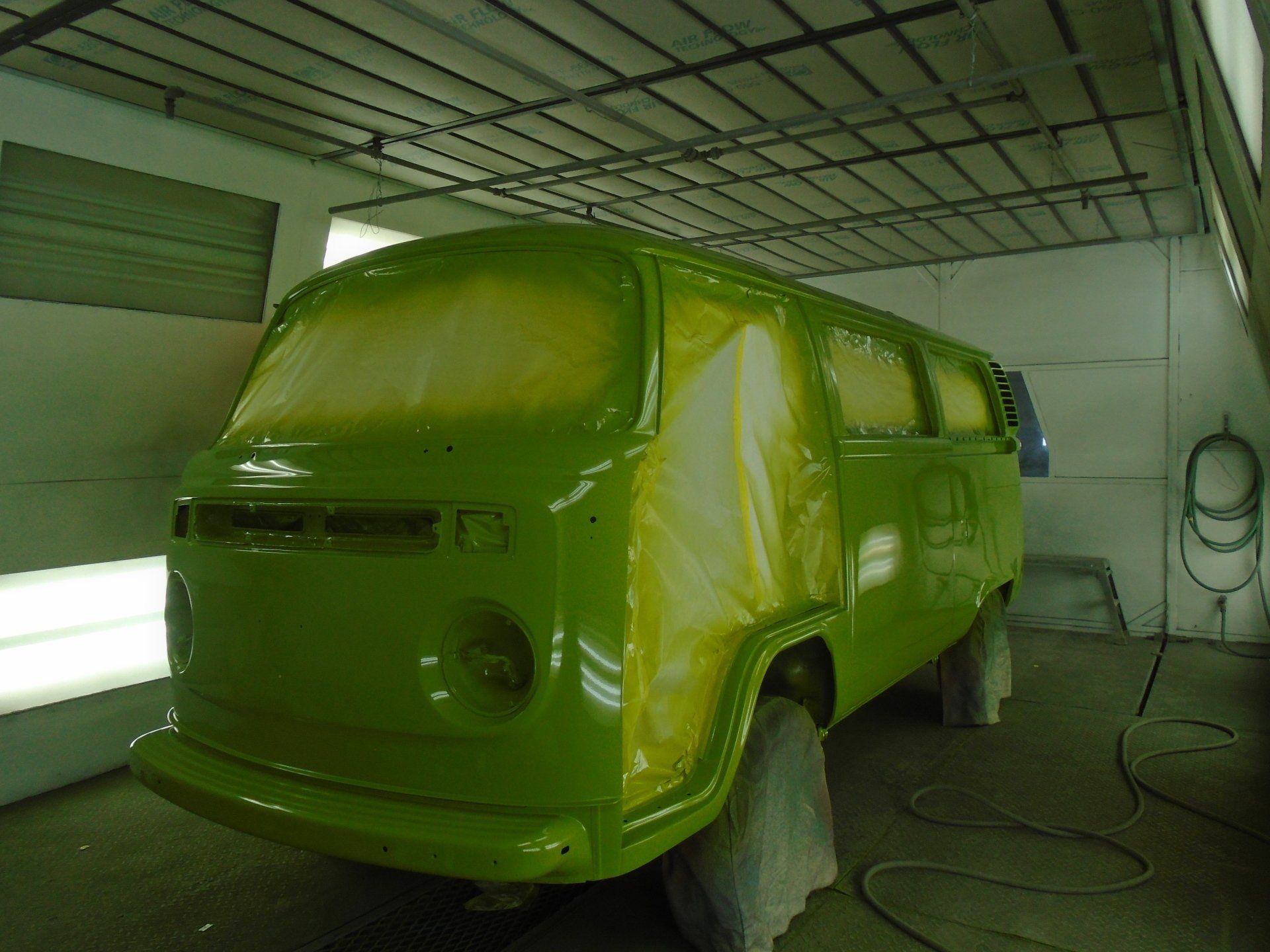 Green Volkswagen van in a paint booth.