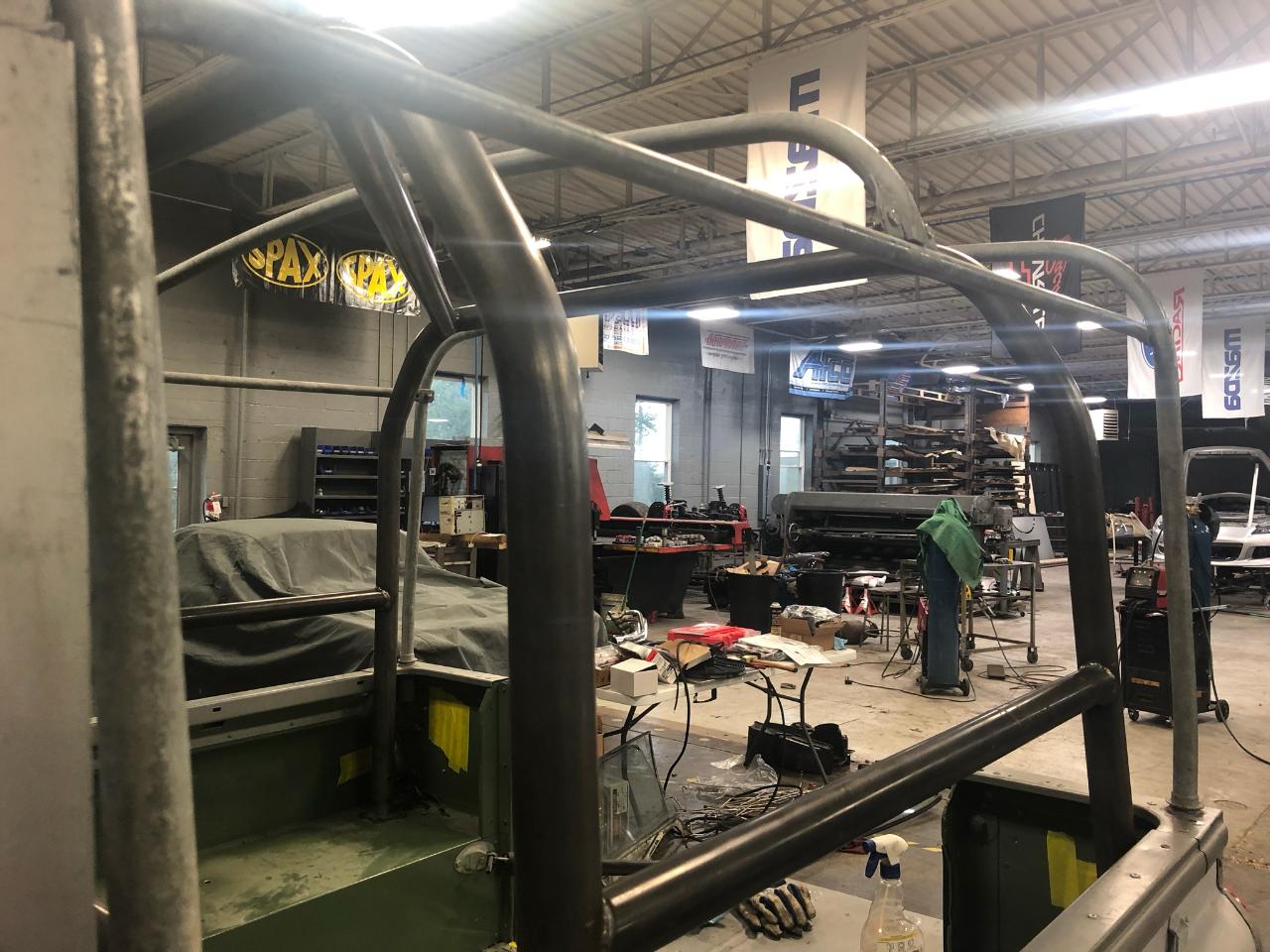 Metal roll cage being fabricated inside a garage; welding in progress.