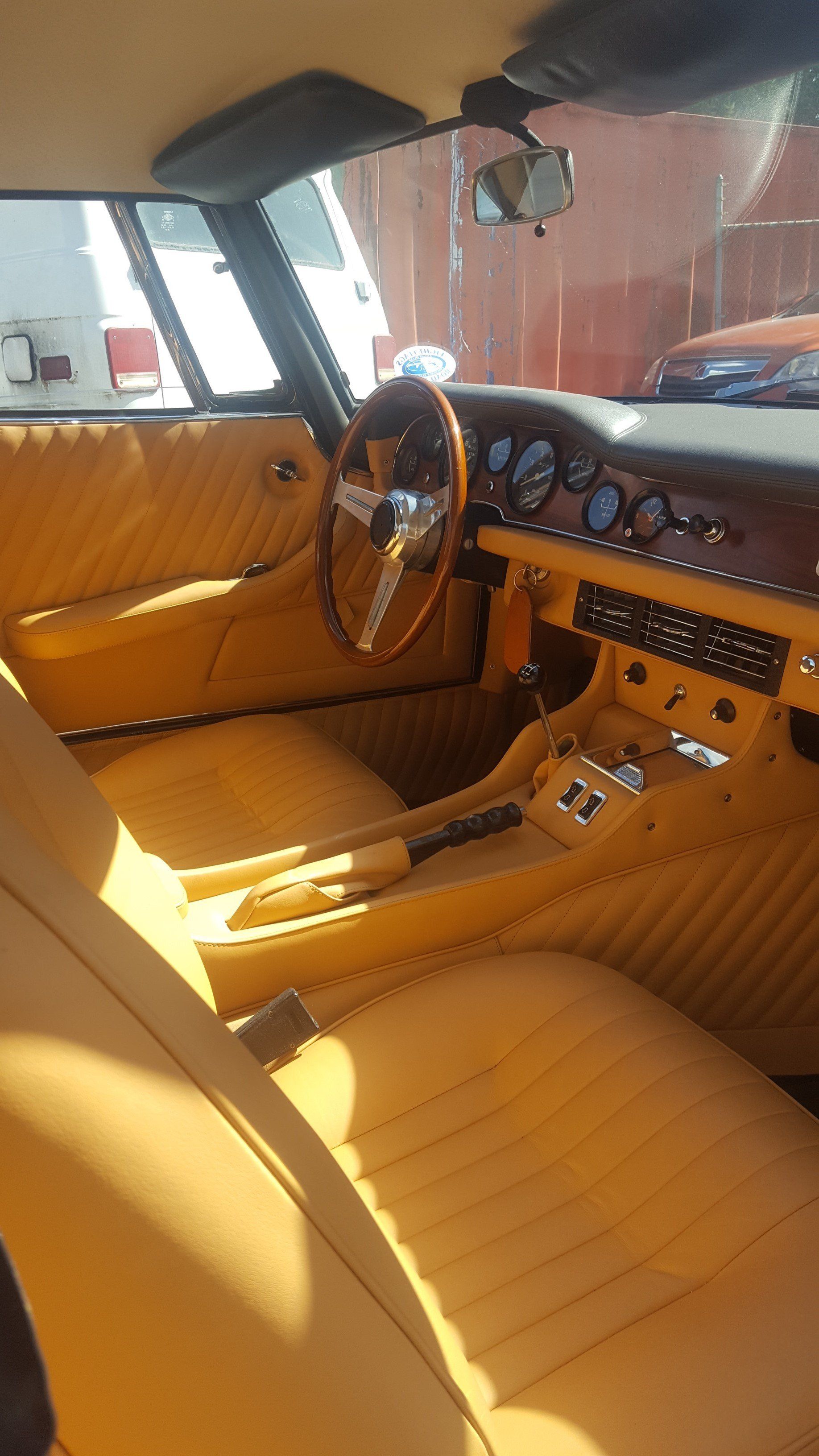 Tan interior of a classic car: seats, steering wheel, dashboard, and door panels.