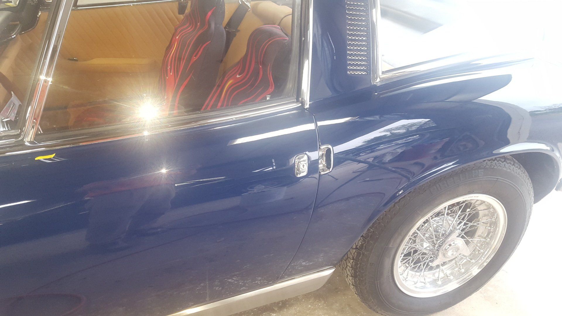 Blue classic car with wire wheels, chrome trim, and tan interior.