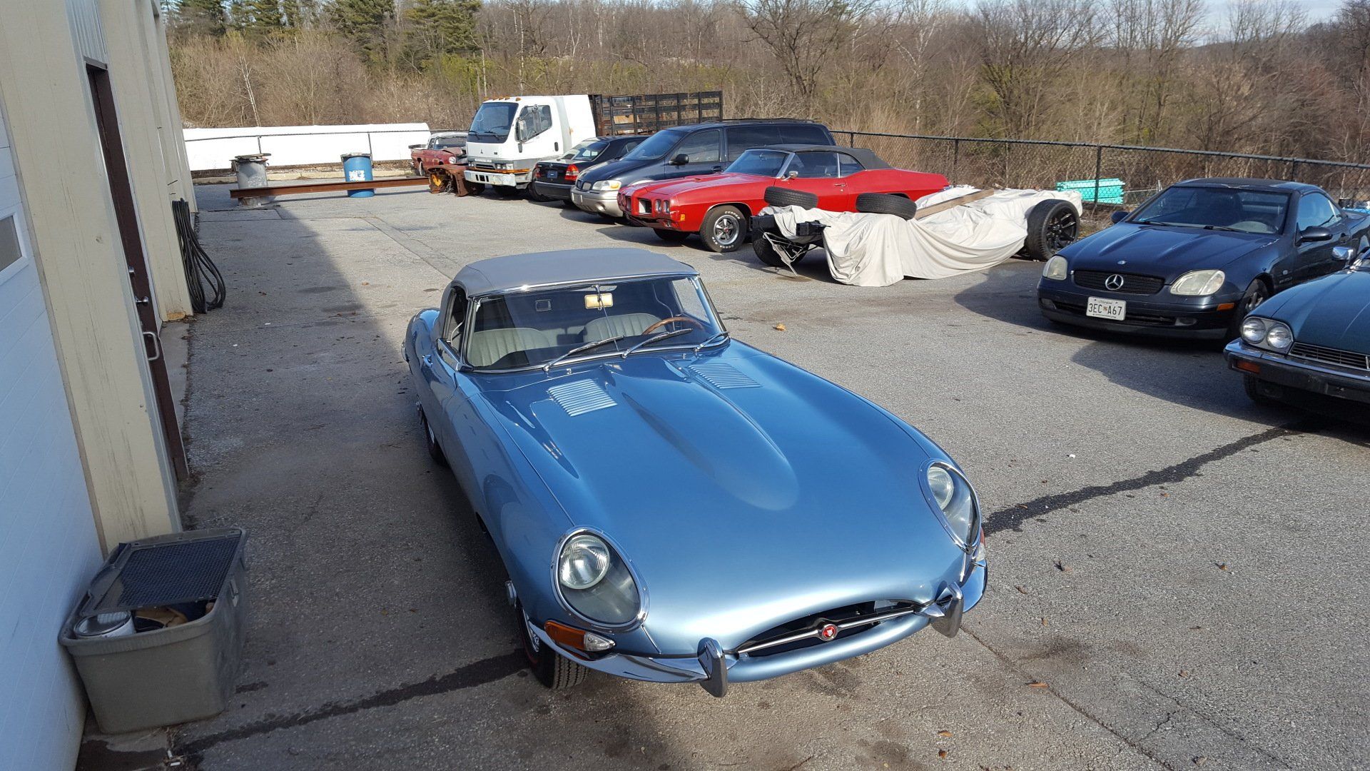 Blue Jaguar convertible parked in a lot with other cars.