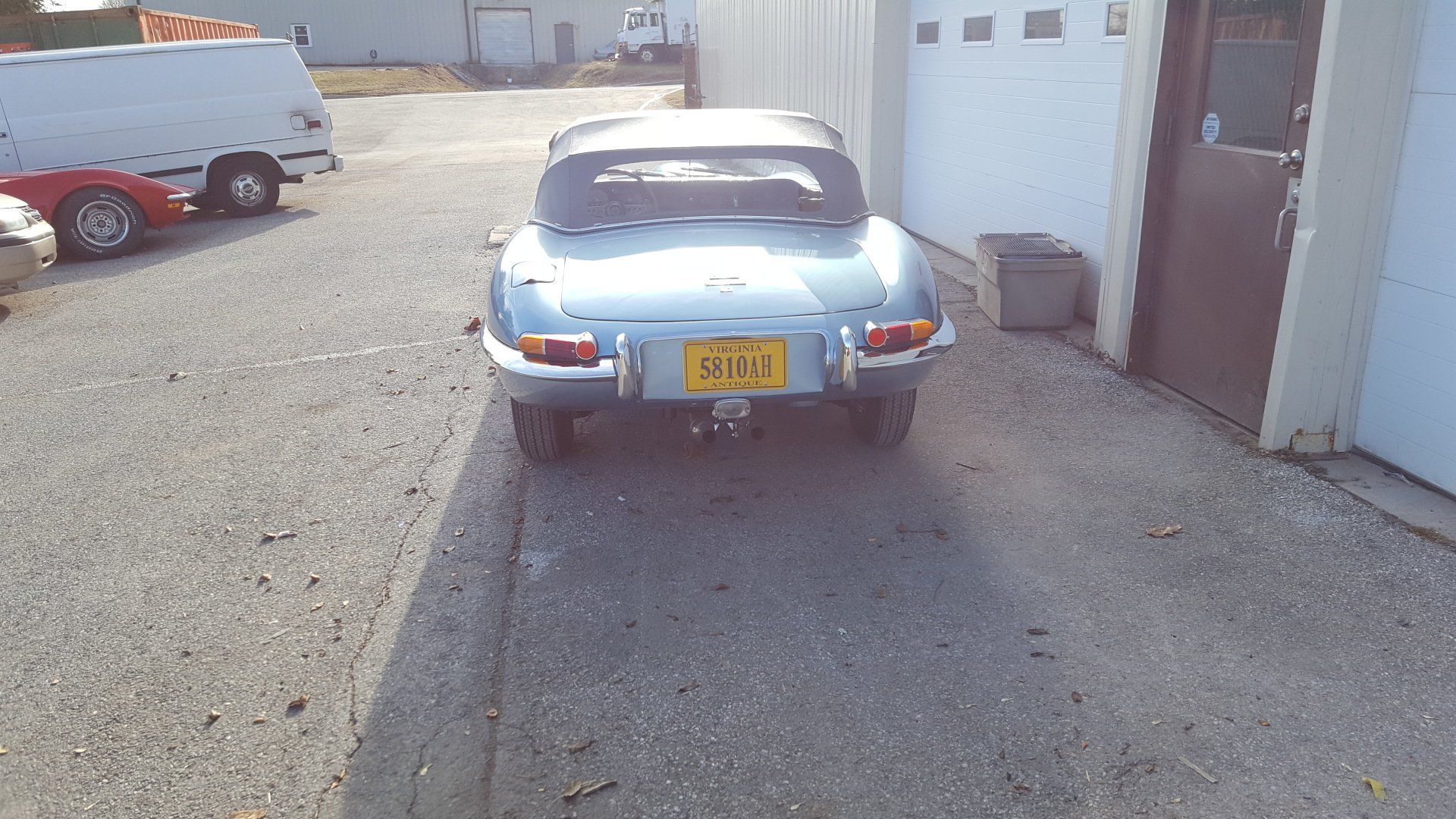 Blue convertible car parked outside a building. Yellow license plate reads 