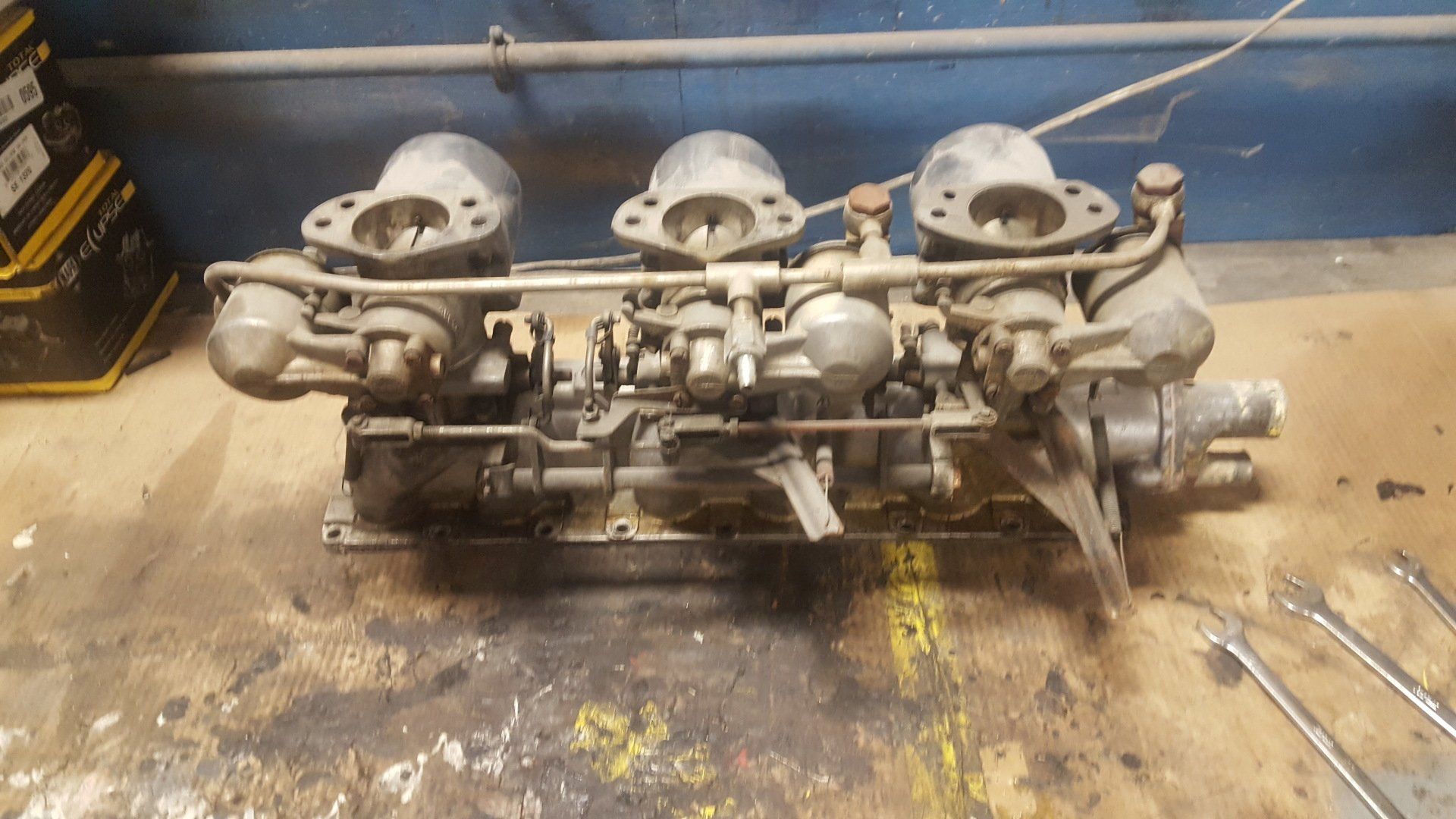 Three-carburetor engine assembly, possibly vintage, on a work surface.