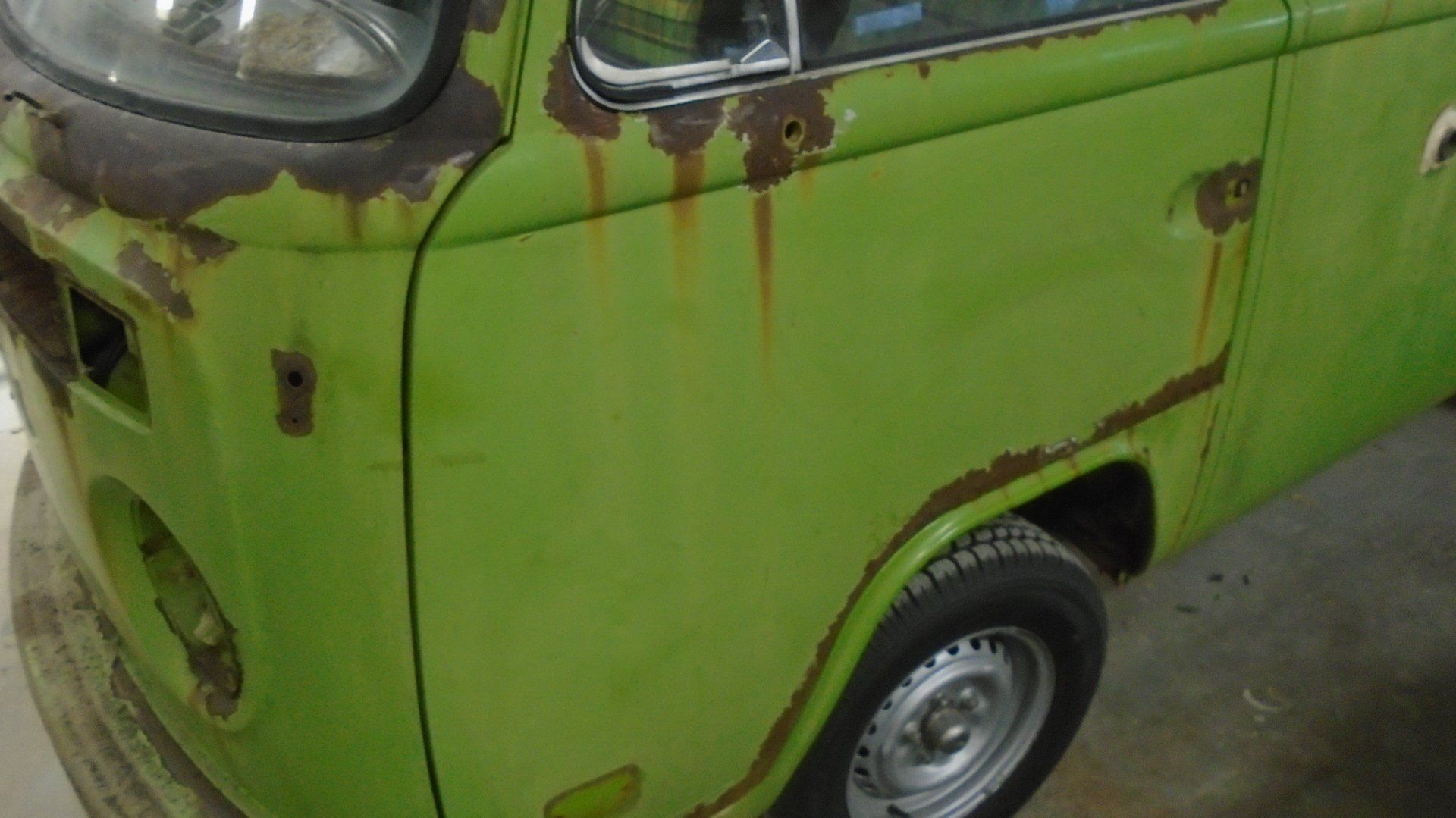 Green and rusty Volkswagen van, showing significant rust damage on the side panel.