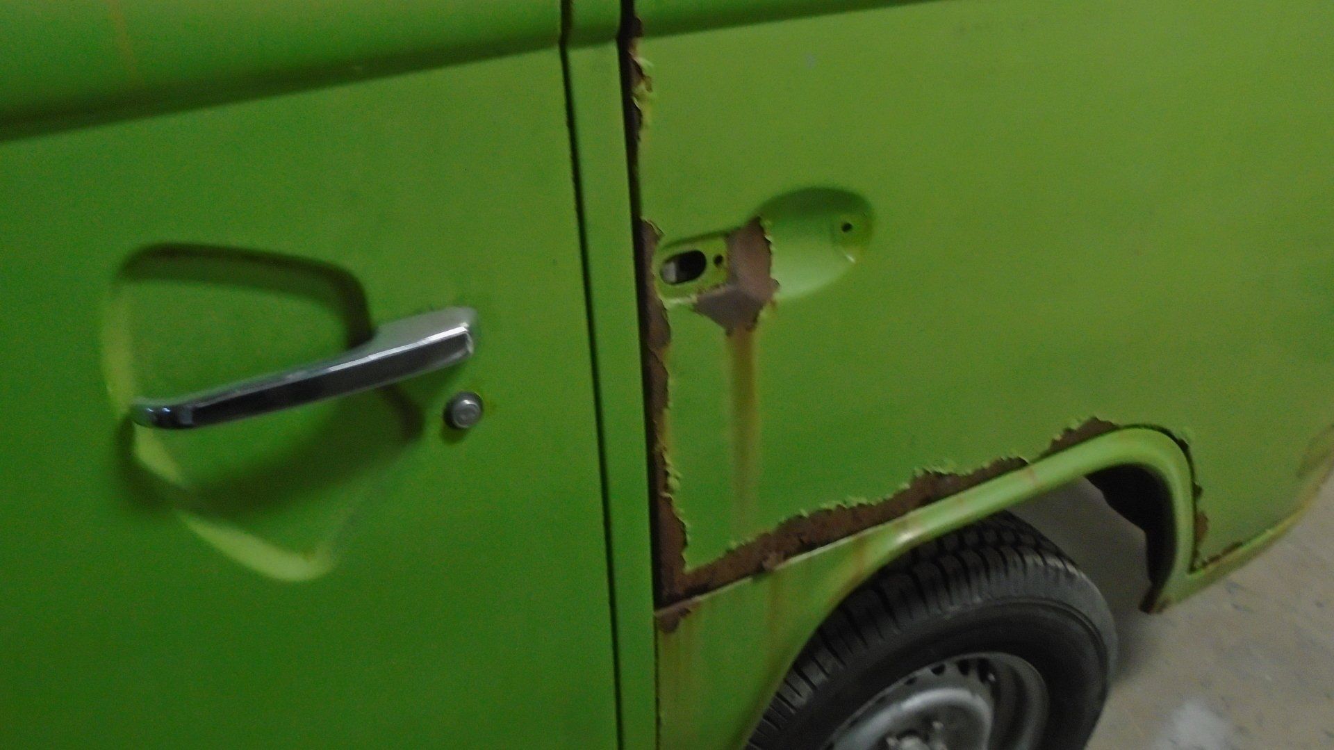 Green car door with rust damage.
