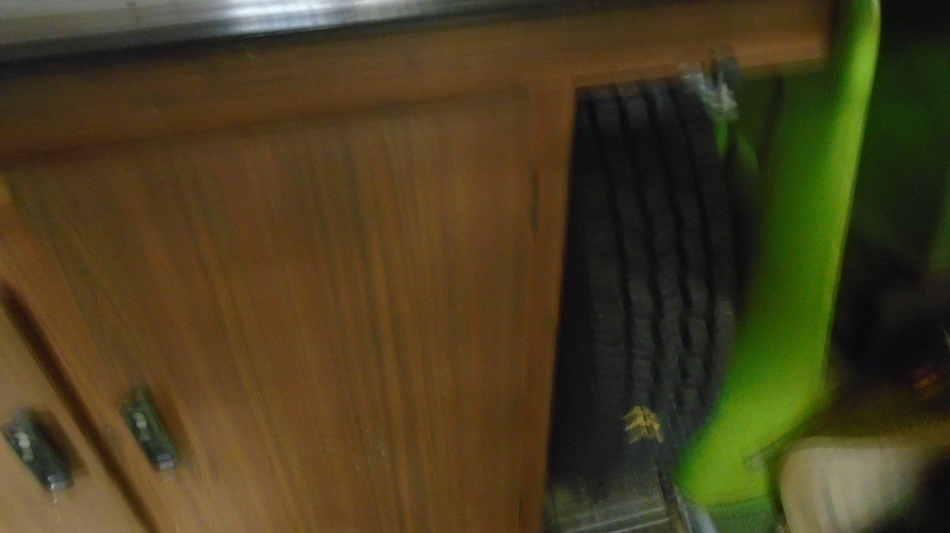 Brown cabinet partially obscuring a black tire, with a green wall in the background.