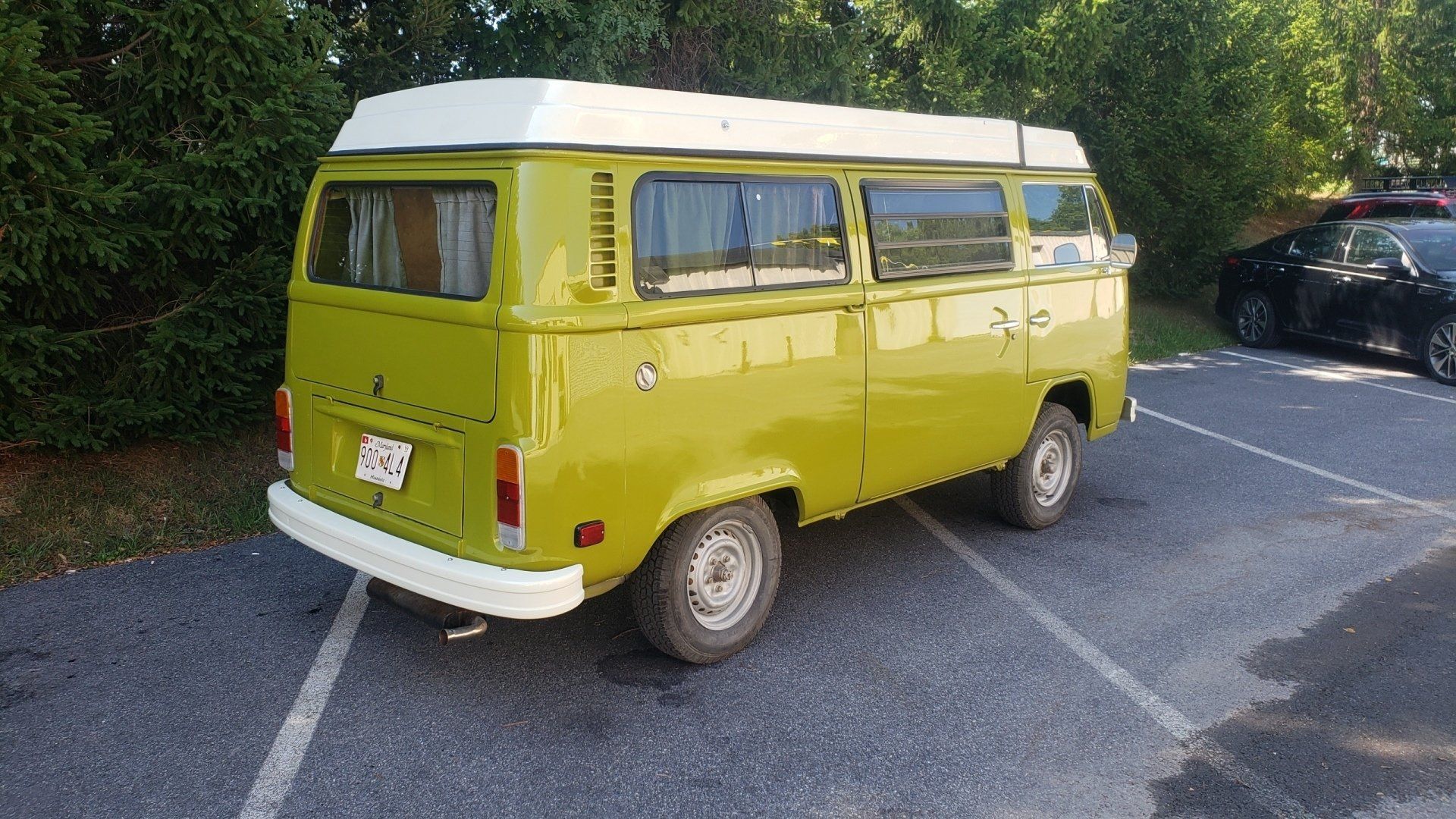 Yellow Volkswagen camper van with white roof parked in lot.
