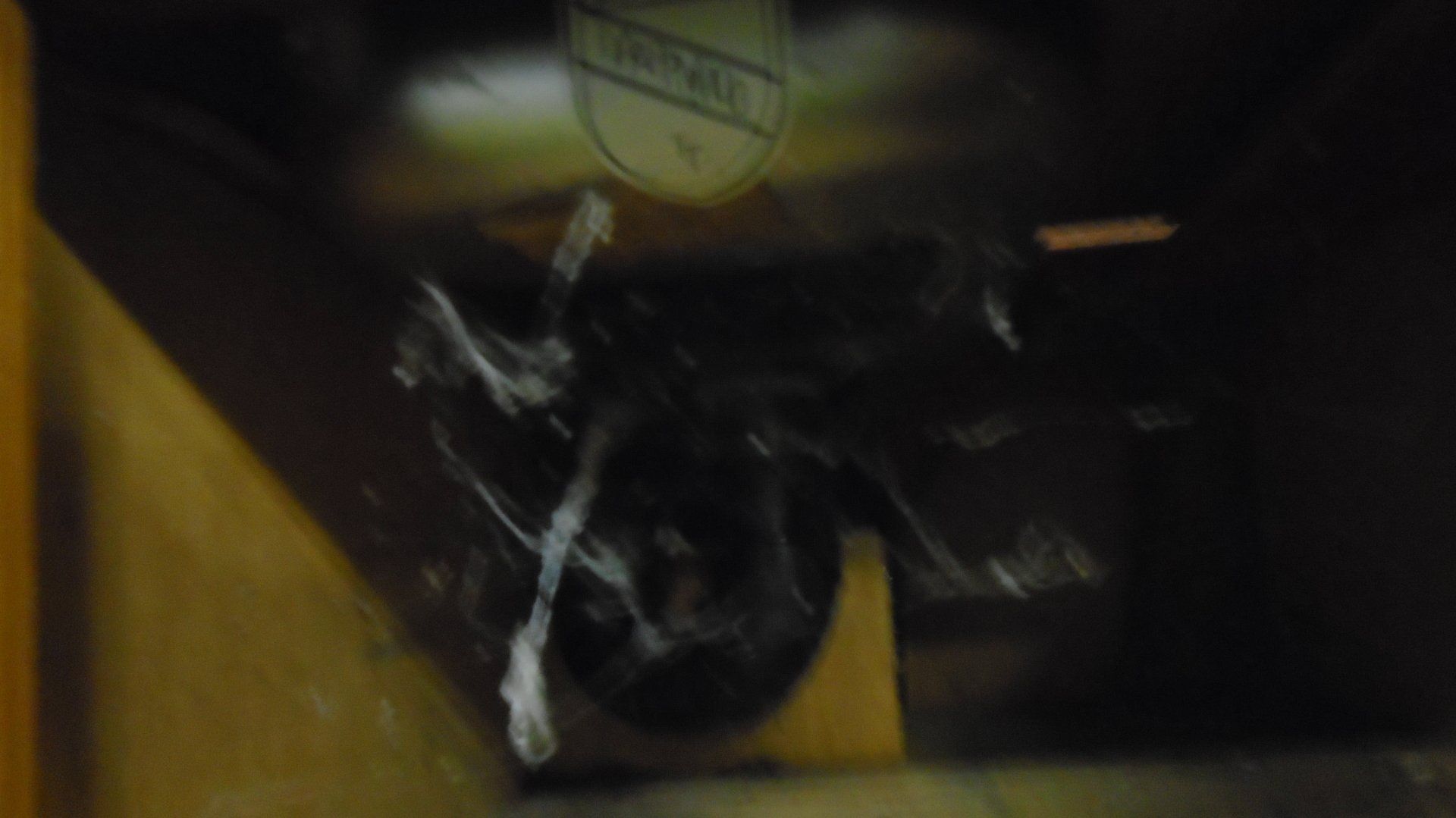 Dark, blurry image of a box with a white design and a shield logo.