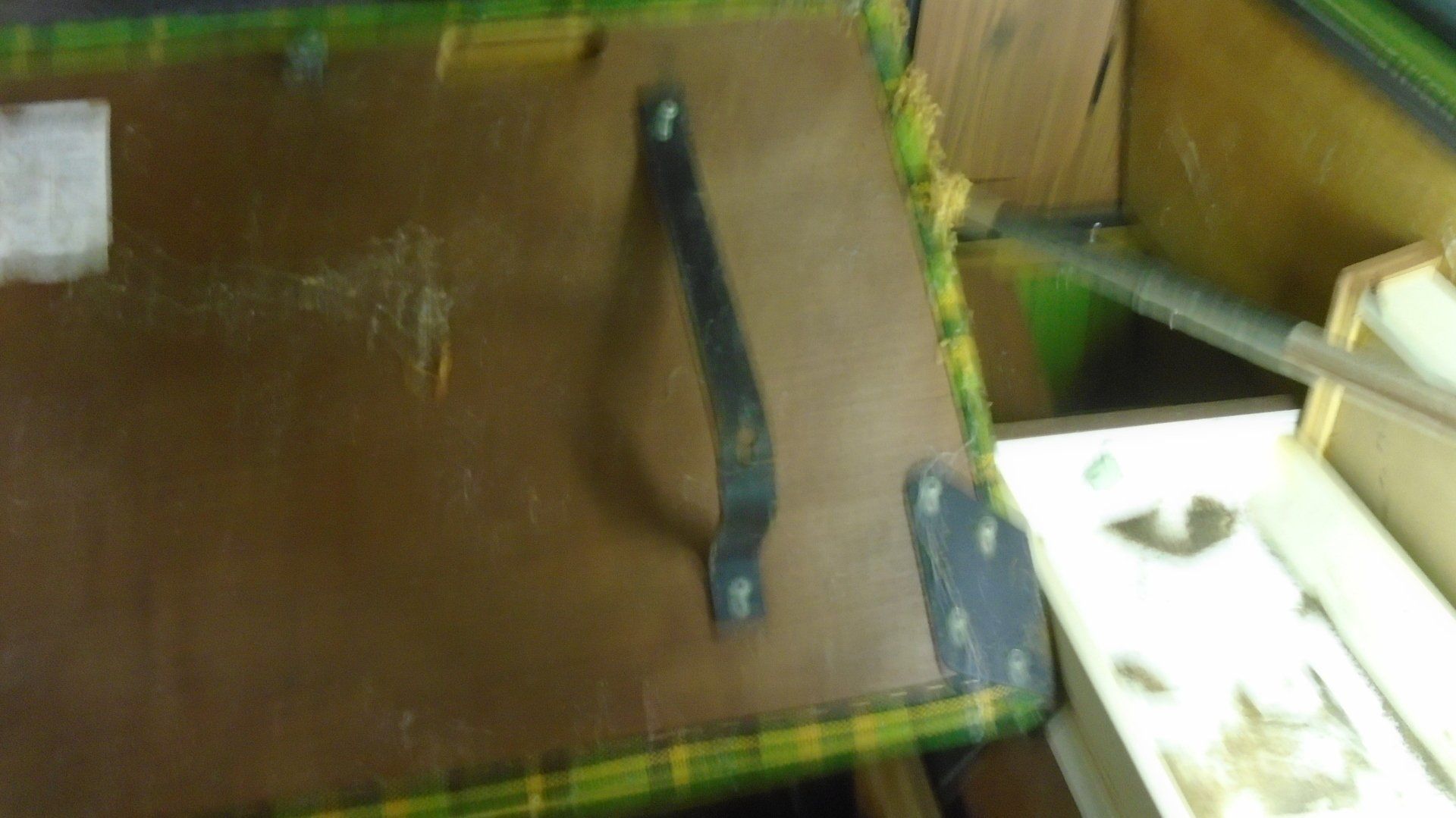 Brown and yellow patterned object with a black handle and metal bracket.