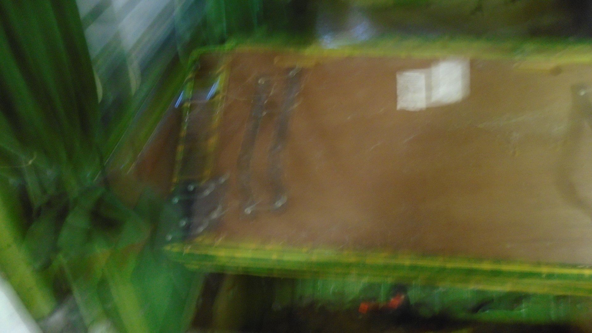 Blurred view of a brown surface with visible streaks, framed by green and yellow edges.