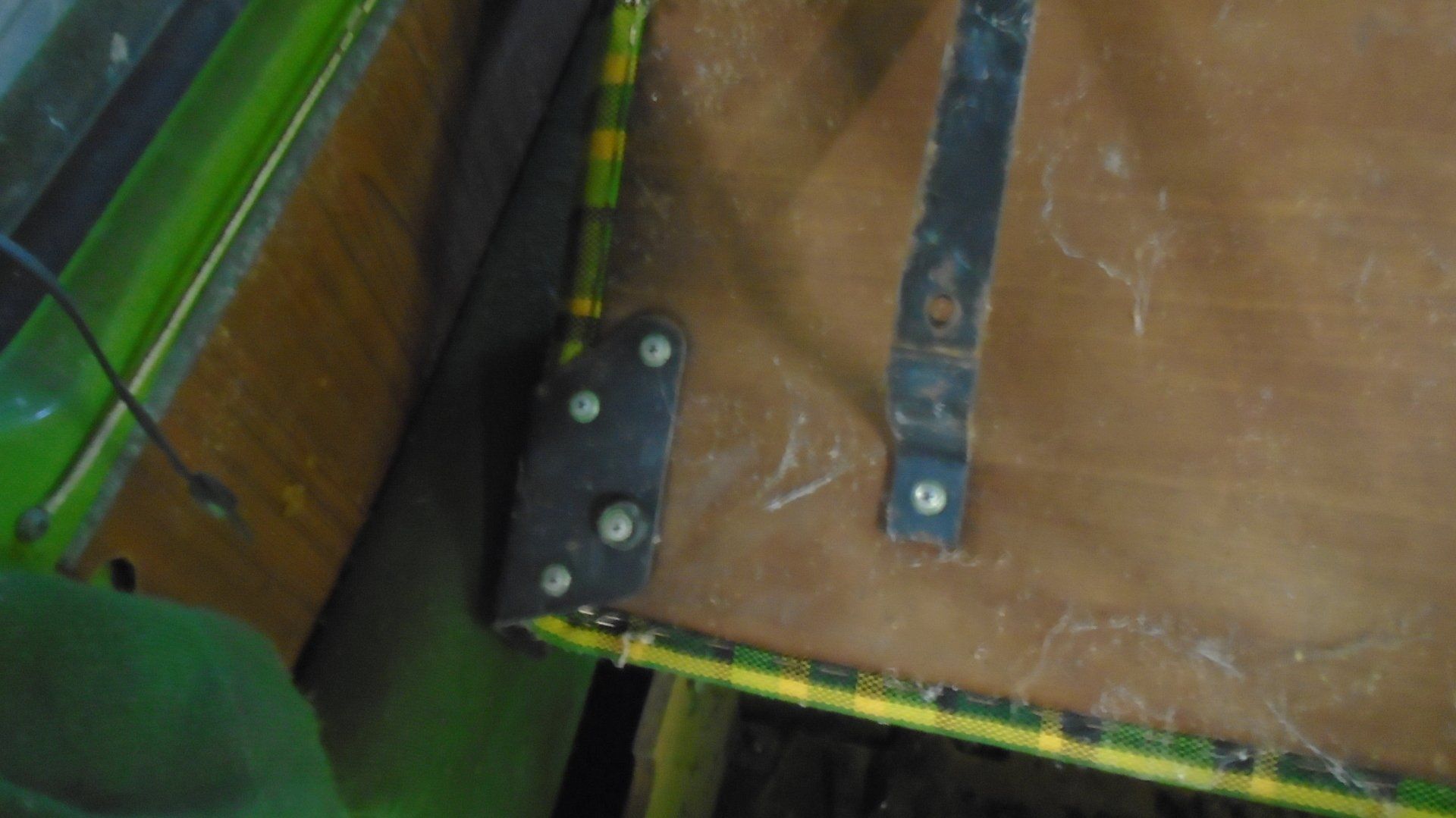Brown wood panel with black metal brackets and fasteners; green edges.