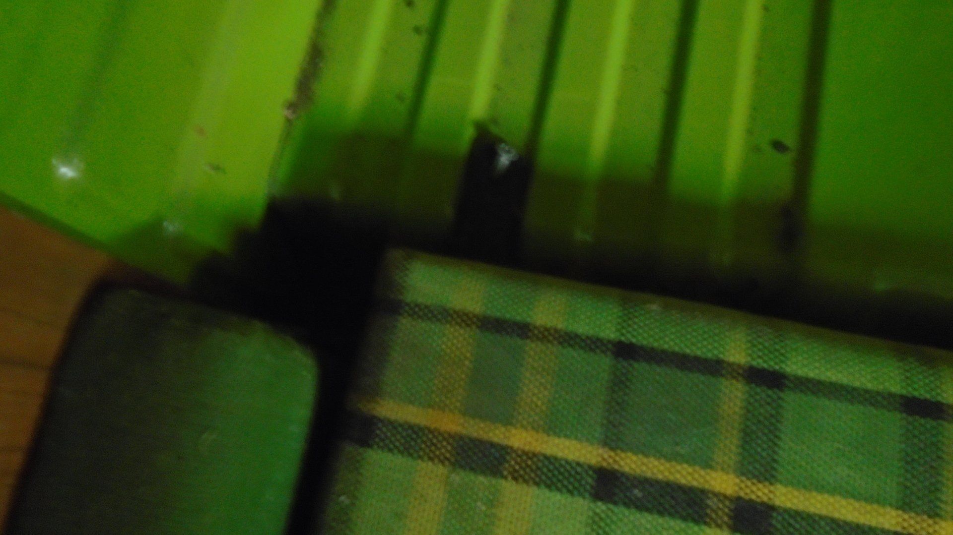 Green surface with a piece of plaid fabric, dark object in the center.