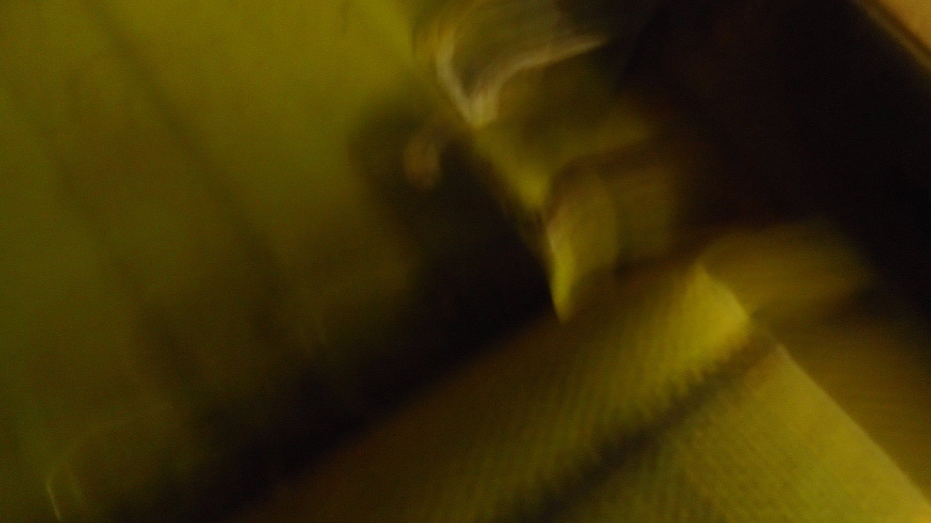 Blurred, yellow-toned image of a hand reaching toward a face.
