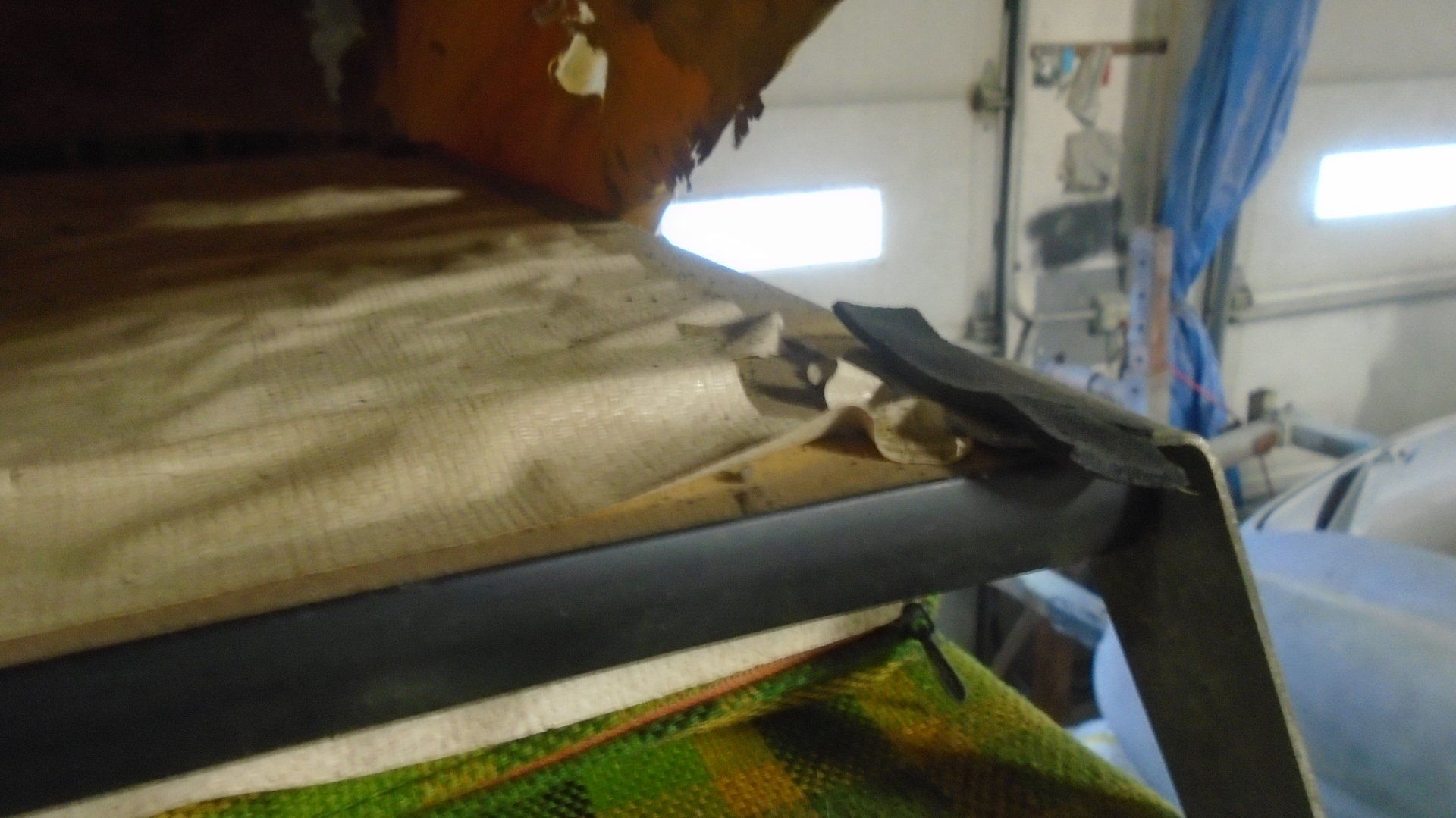 Tan fabric and dark metal frame inside a garage, possibly a car roof in repair.