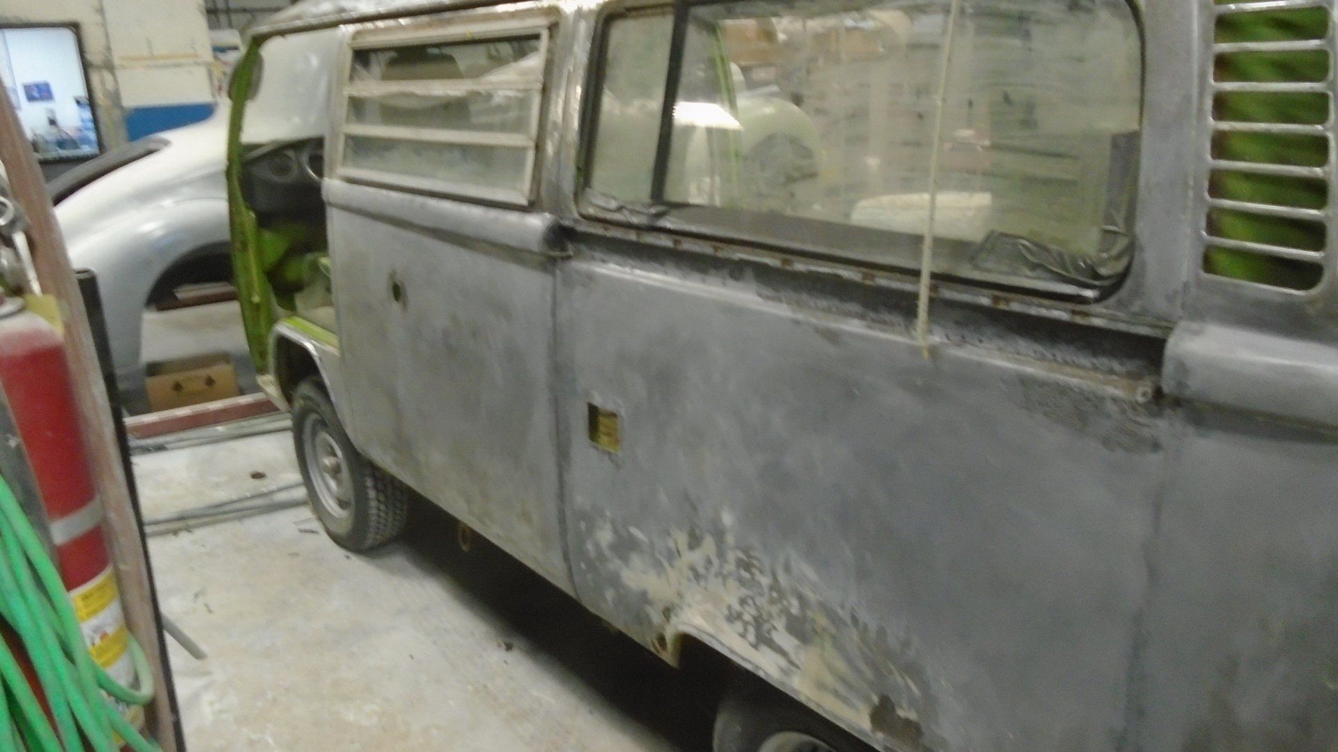 Gray VW bus undergoing restoration in a shop.