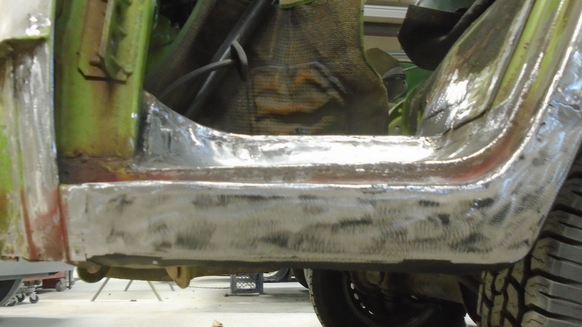Metal car body section being repaired with welding.