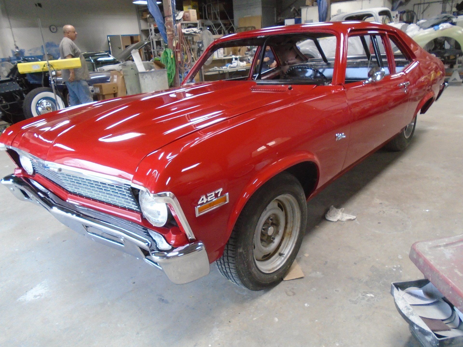 Red restored vintage Chevy Nova in a garage.