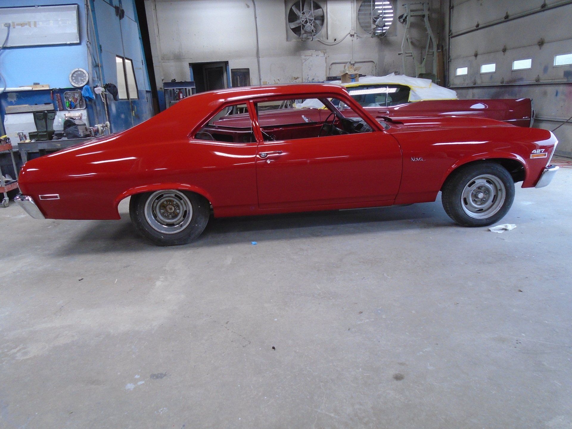 Red 1970s Chevrolet Nova in a garage.