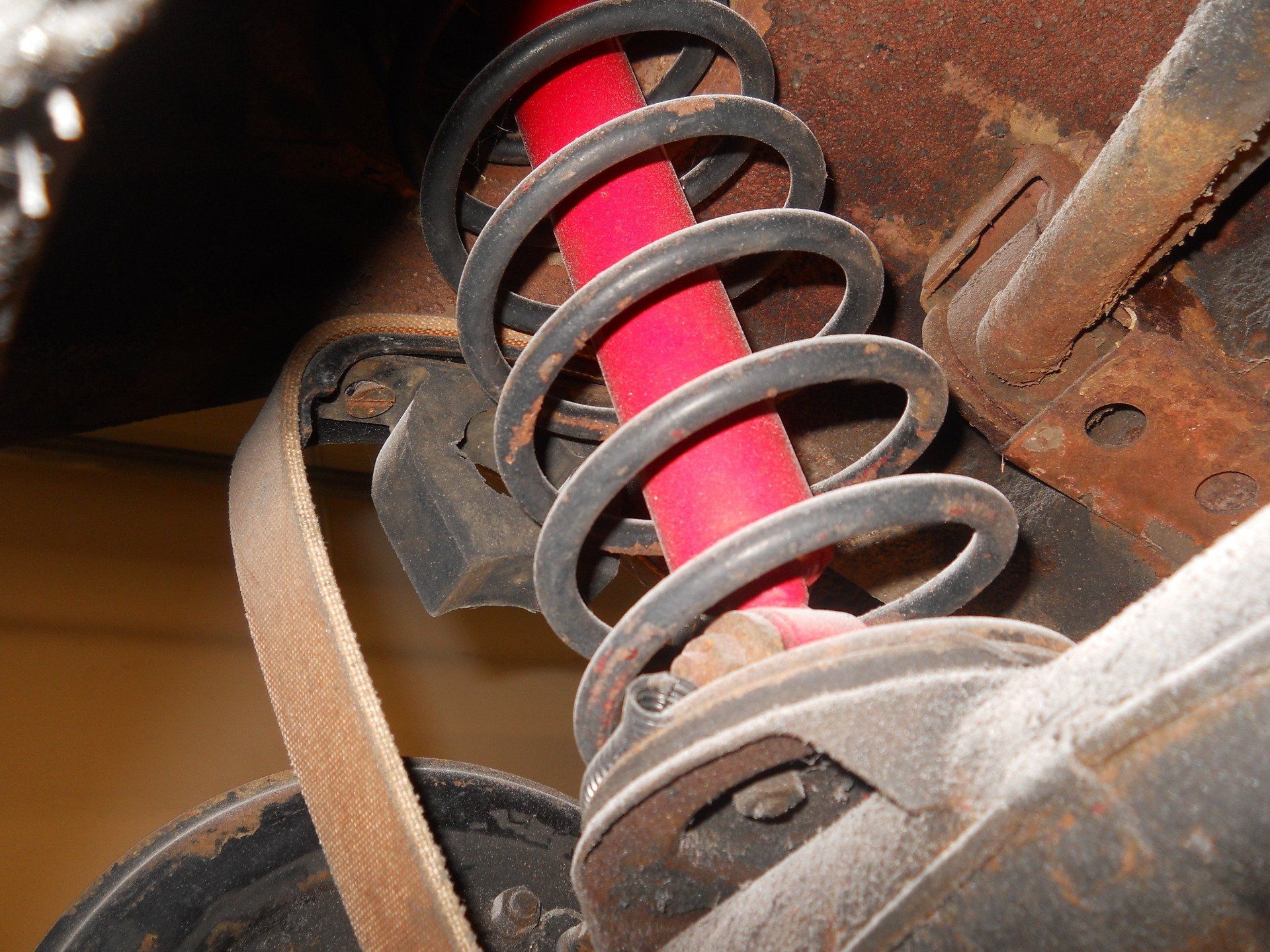 Red shock absorber with black coil spring, part of a vehicle's suspension system.