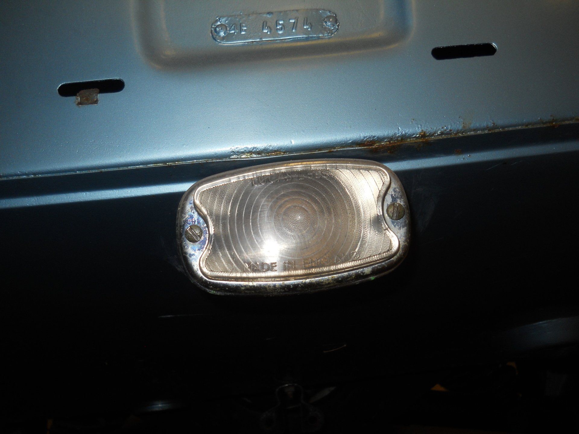 Close-up of a clear, oval-shaped car light with chrome trim on a blue car.