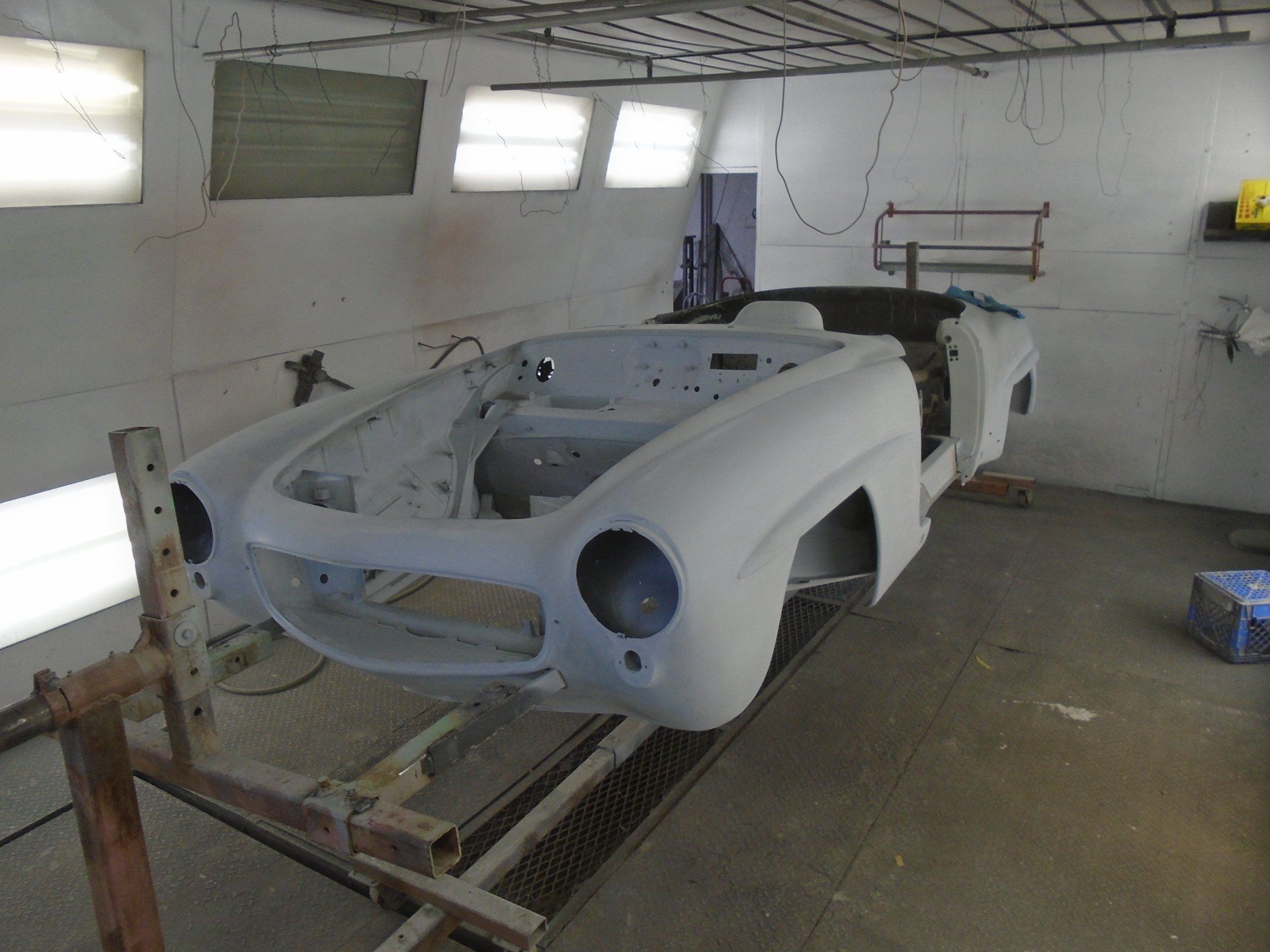 Classic car body in a paint booth, primed and ready for paint.