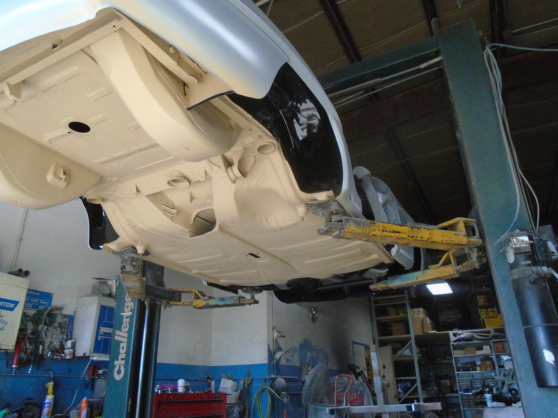 Underside of a car on a lift in a garage, freshly painted white.
