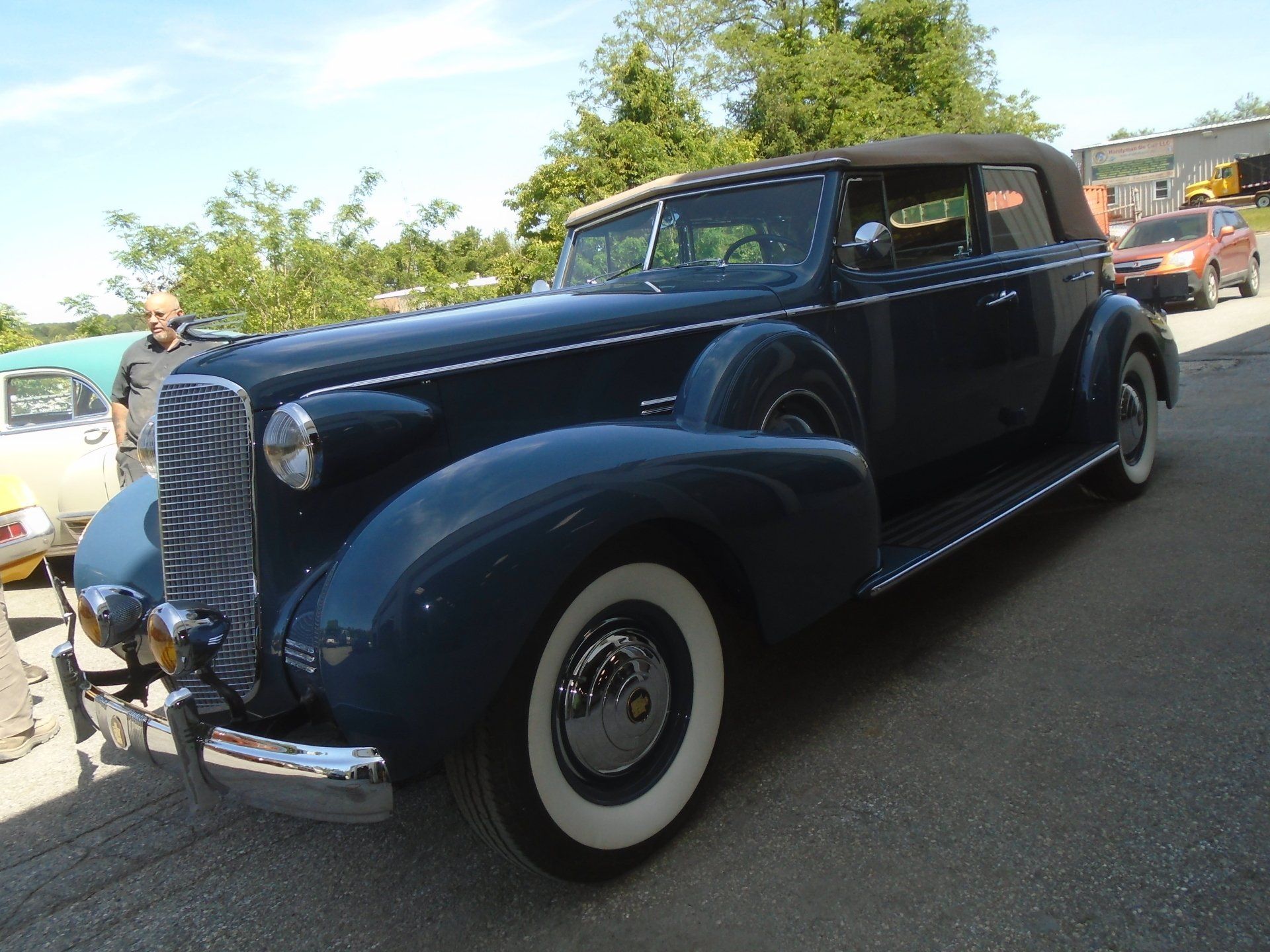 Dark blue vintage convertible car with white-walled tires, chrome details, and a black convertible top.