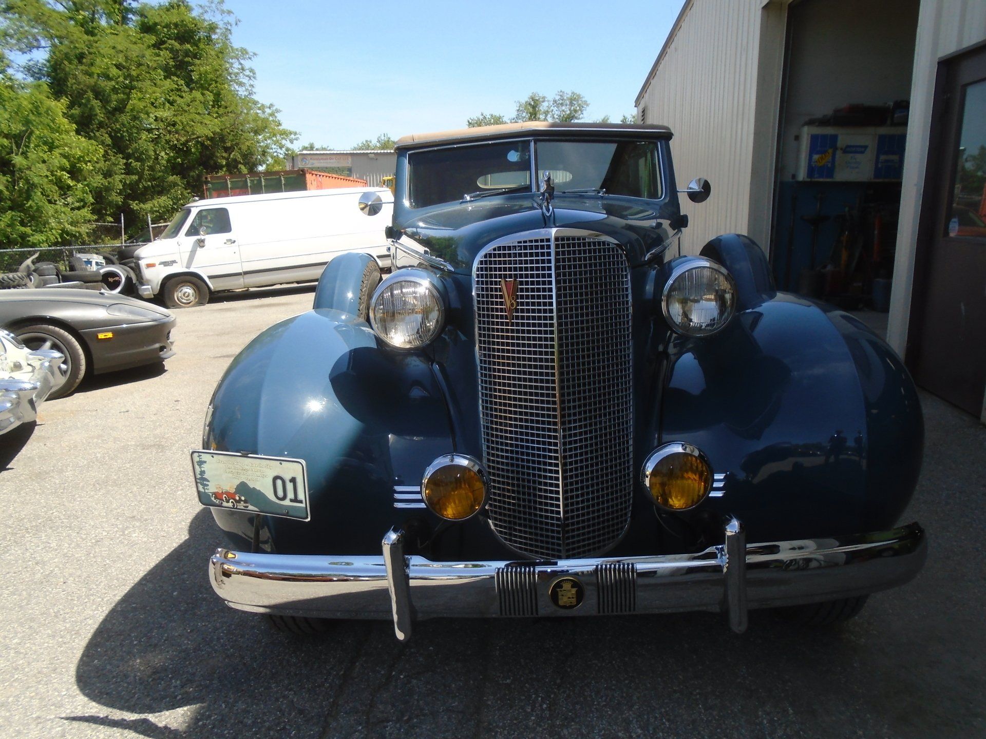 Blue classic car parked outside a building with its front facing the camera.