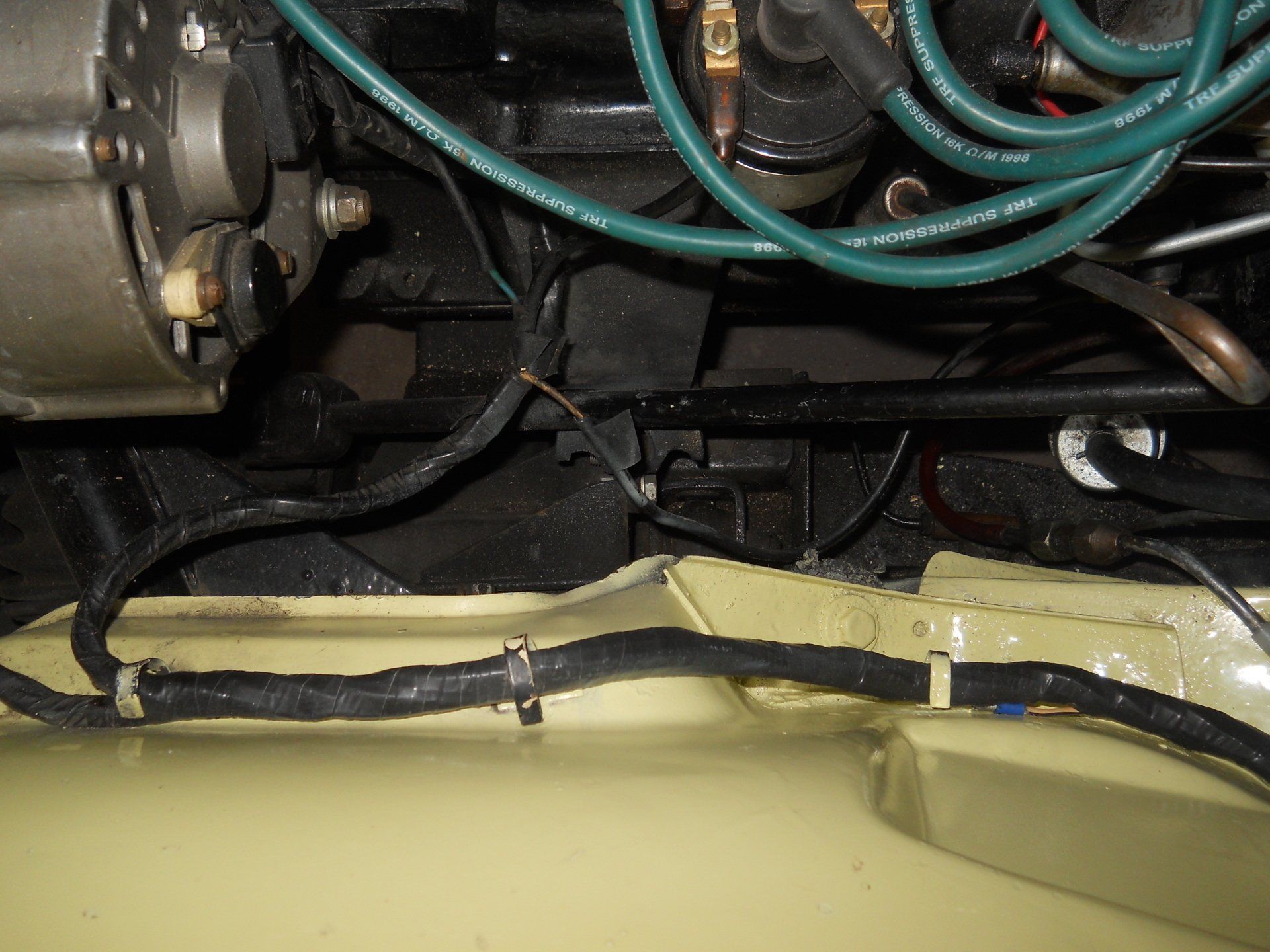 Black engine components, wires, and cabling against yellow car frame.