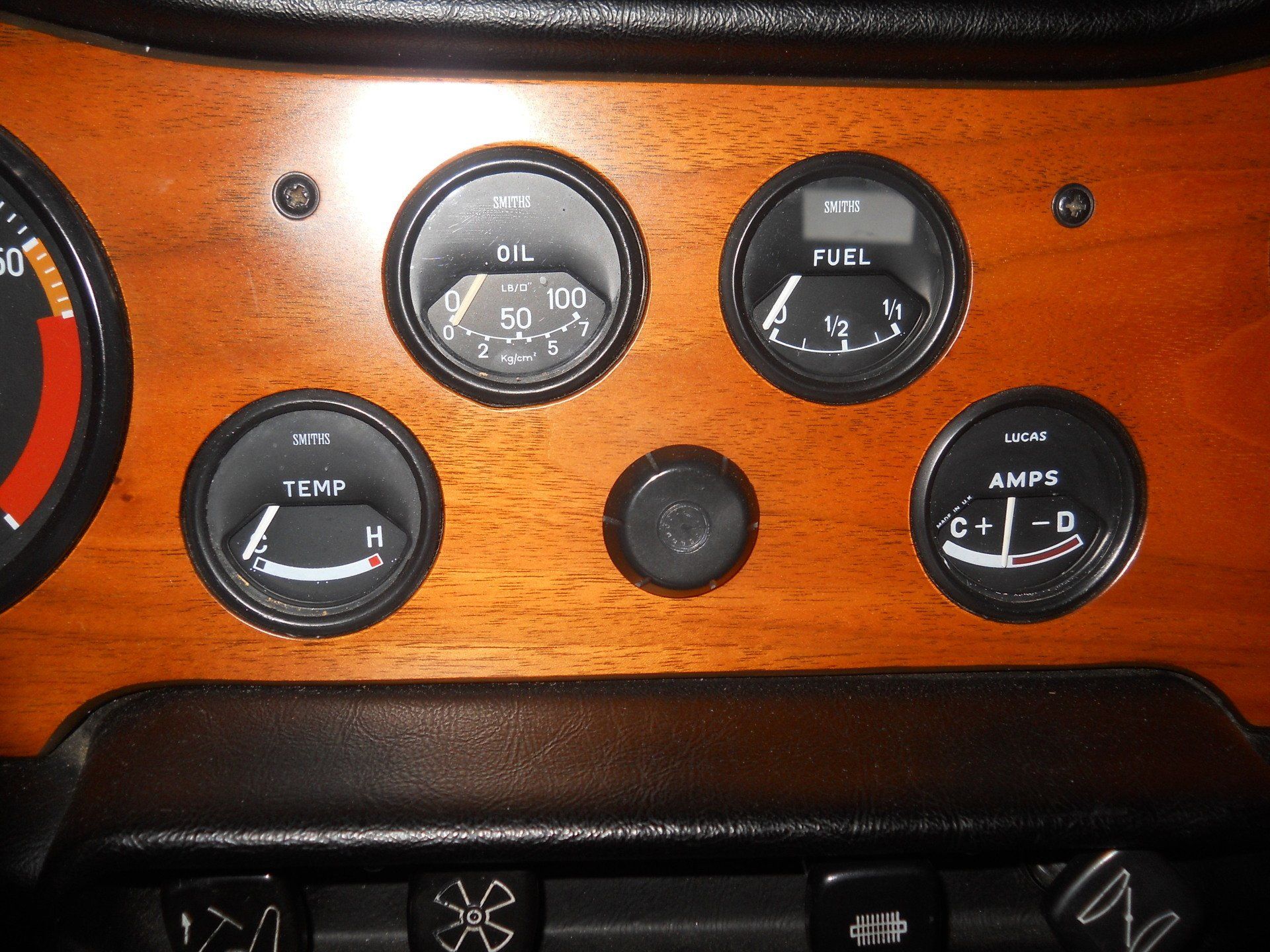 Car dashboard with woodgrain finish; gauges for oil, fuel, temperature, and amps.