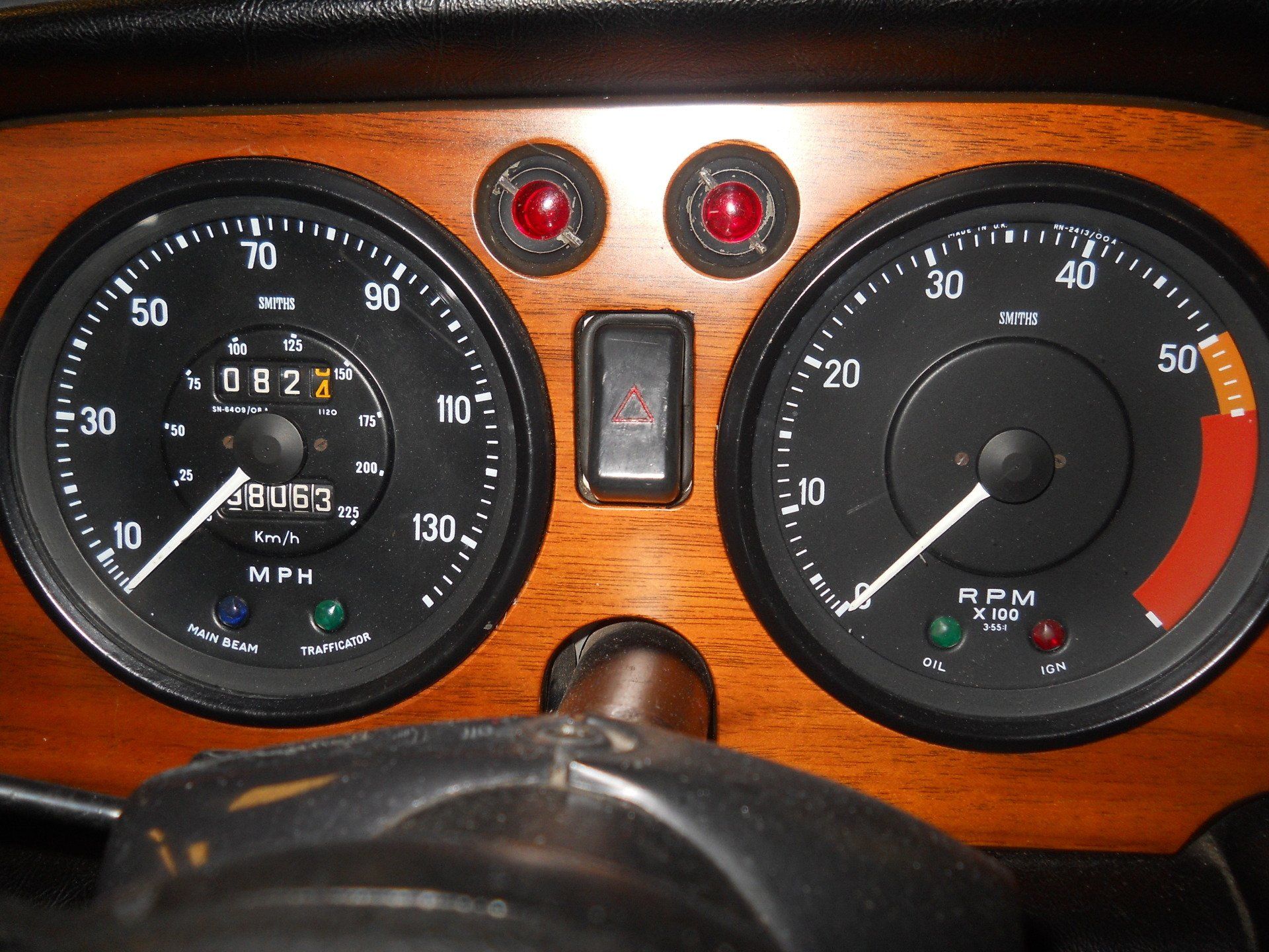 Dashboard with speedometer, tachometer, warning lights, and wooden paneling.