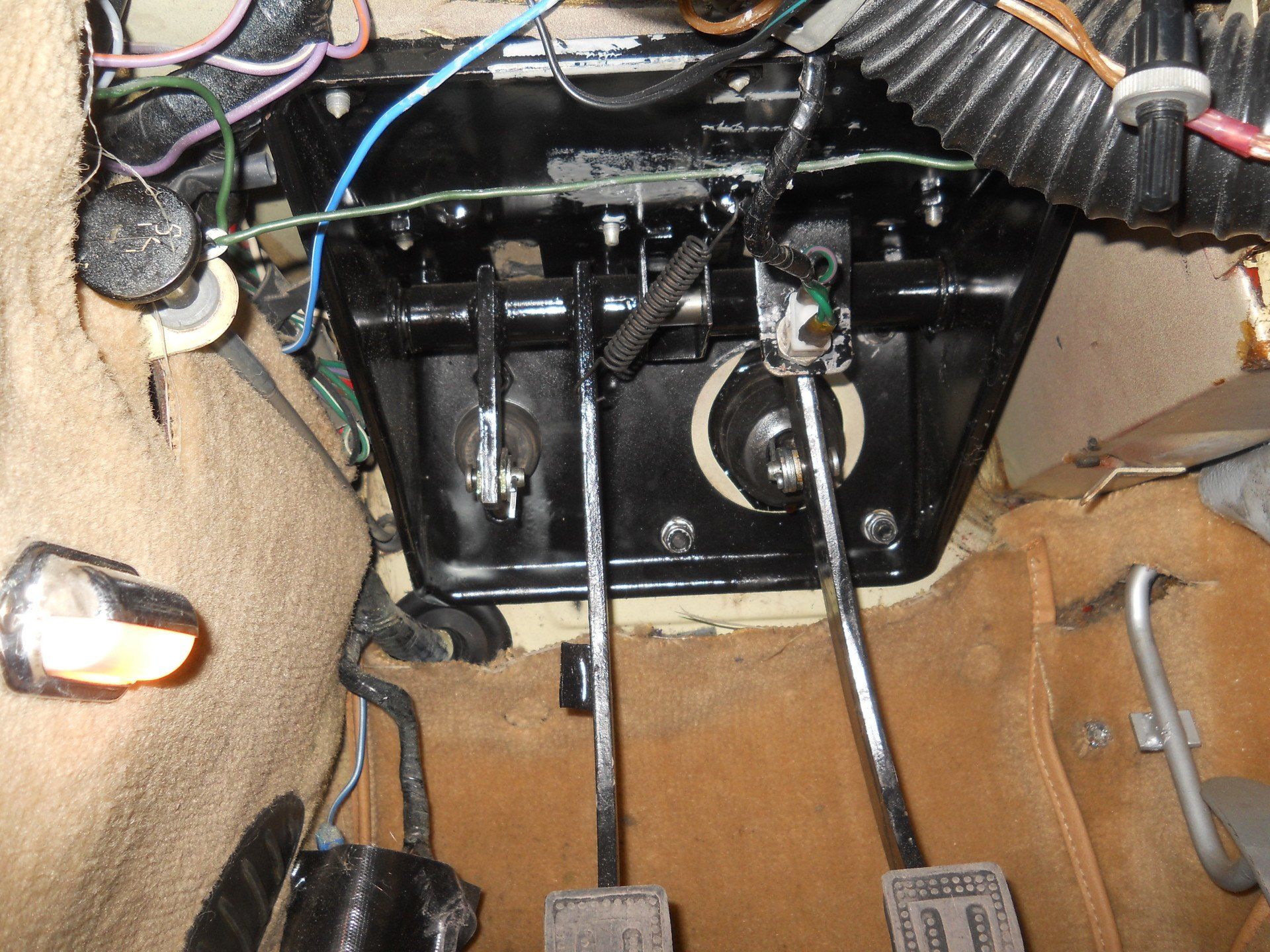 Interior car view: brake, clutch, accelerator pedals, and related components under dashboard.