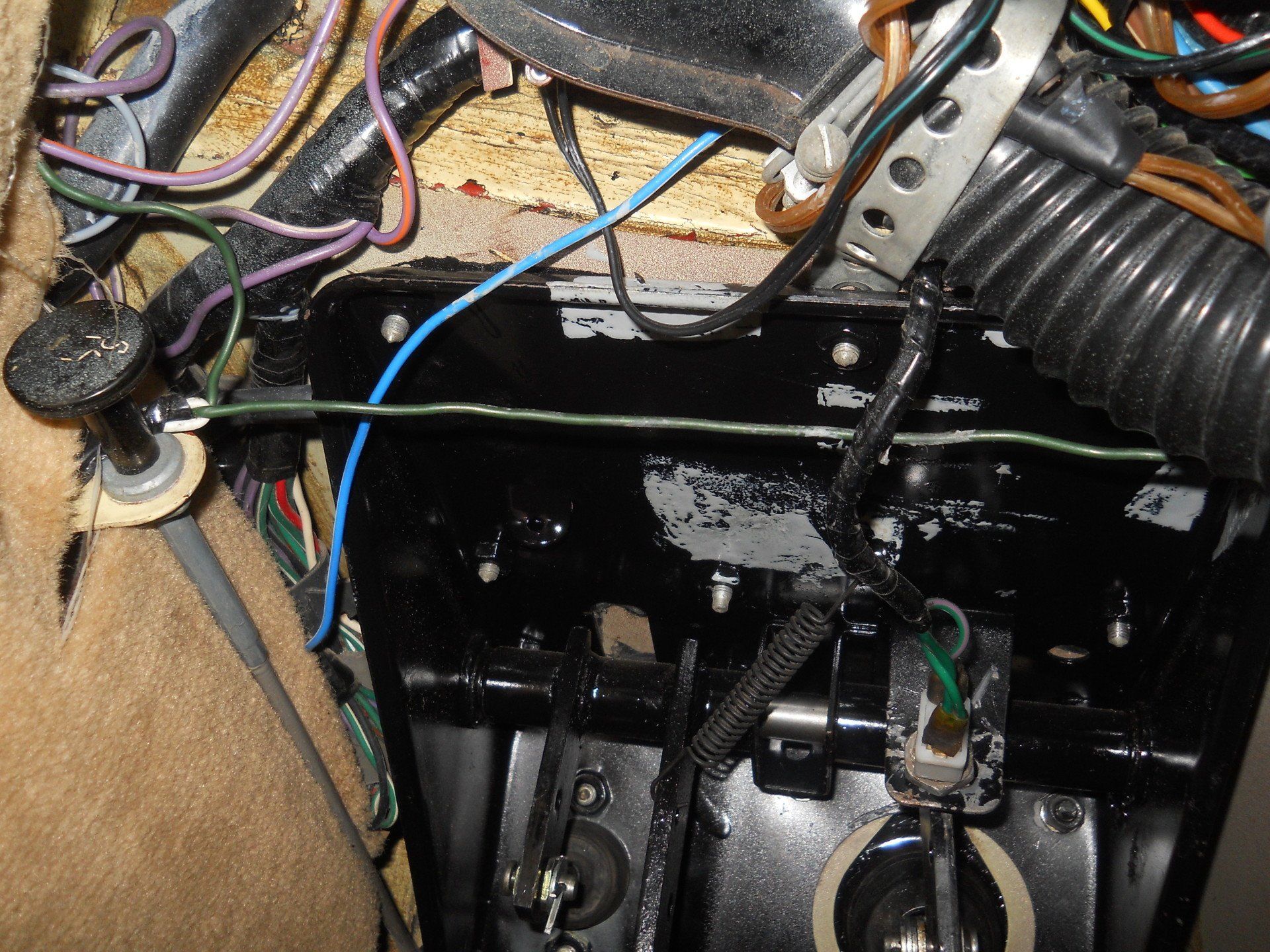 Black dashboard with wiring. Blue, green, and other colored wires present. Black pedal and knob visible.