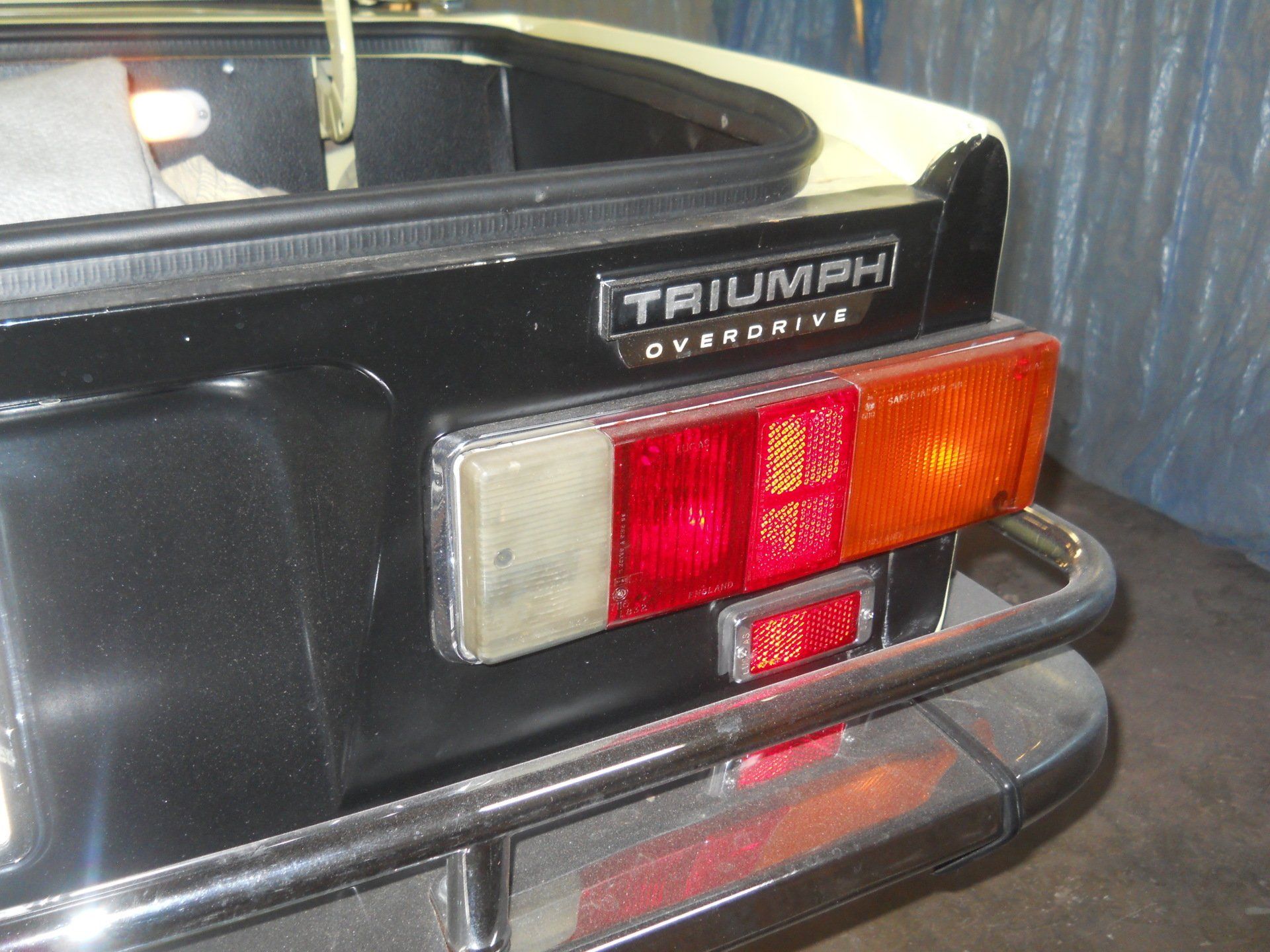 Rear section of a black Triumph sports car, showing taillights and 