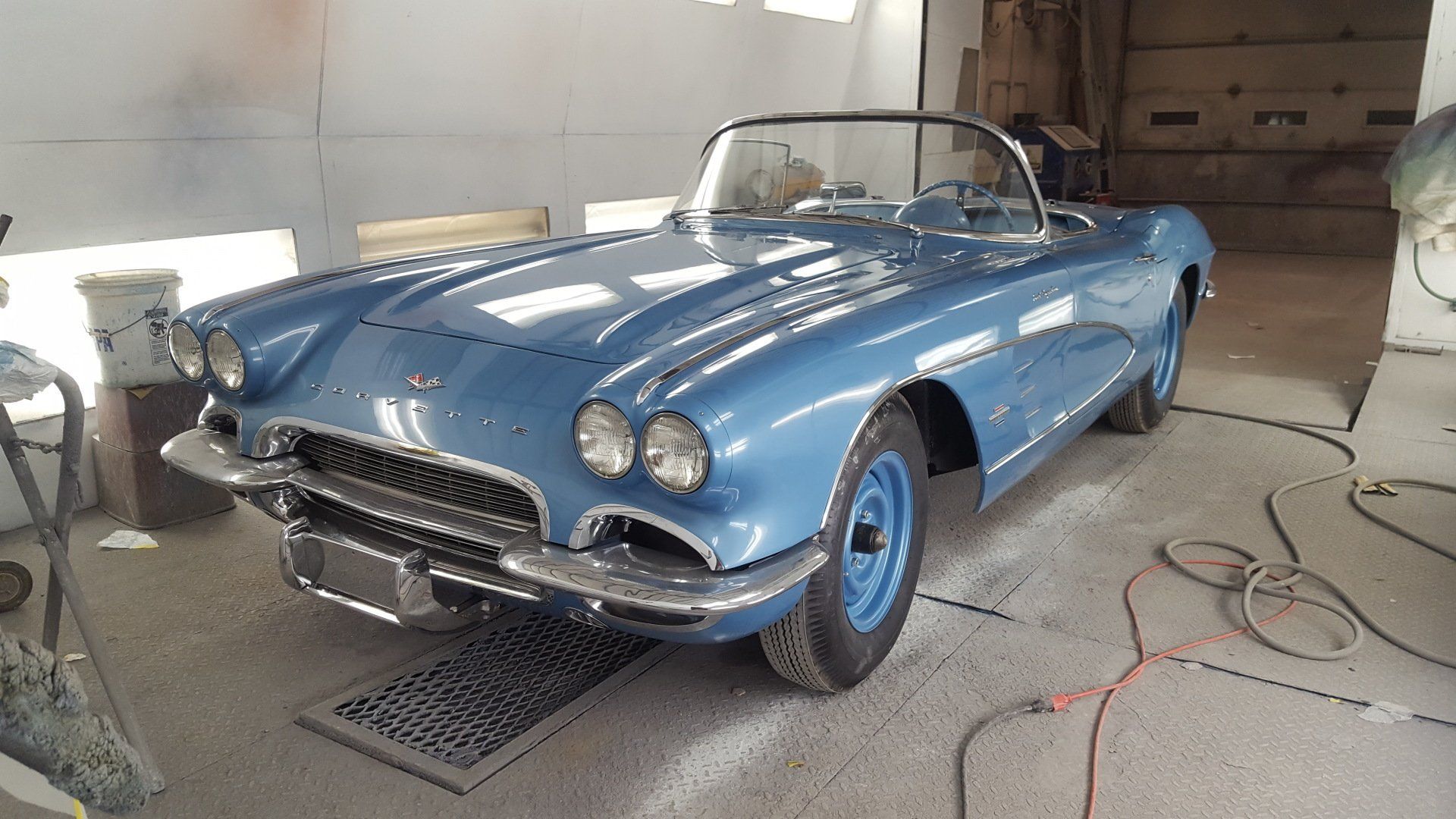 Blue classic Corvette convertible in a garage.